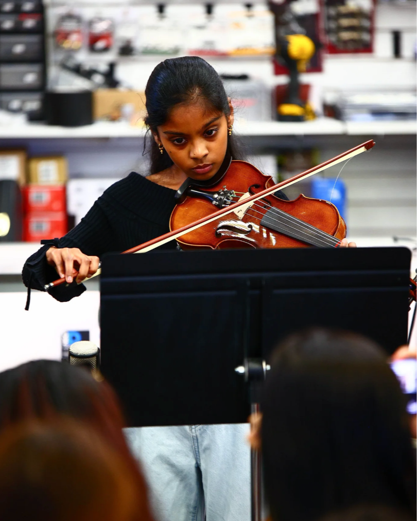 Young girl playing the violin in a music store or practice room.