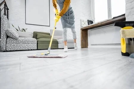 Person cleaning the floor with a mop in a modern living room.