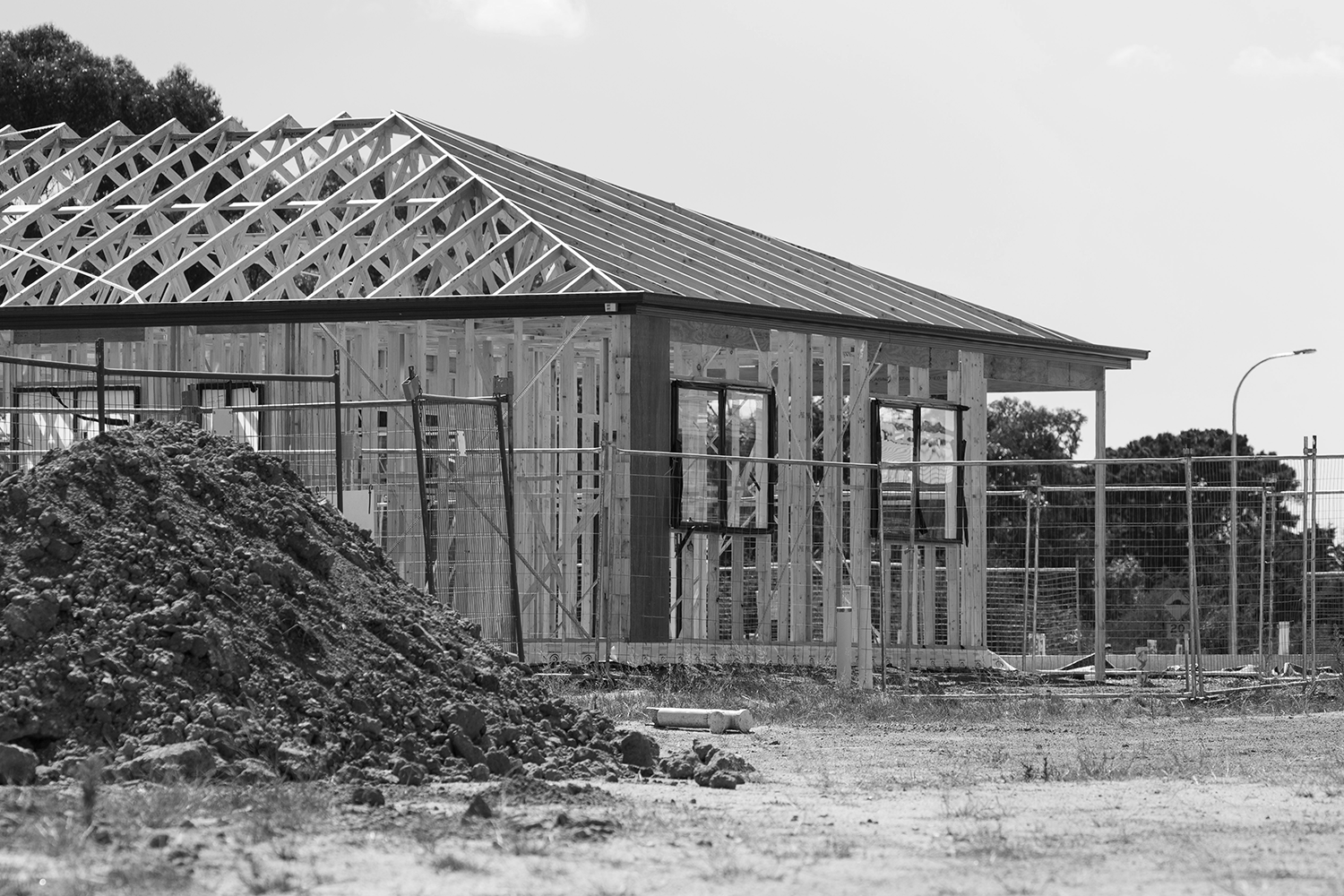 Construction site with a building under construction, wooden framing, and a pile of dirt in the foreground.