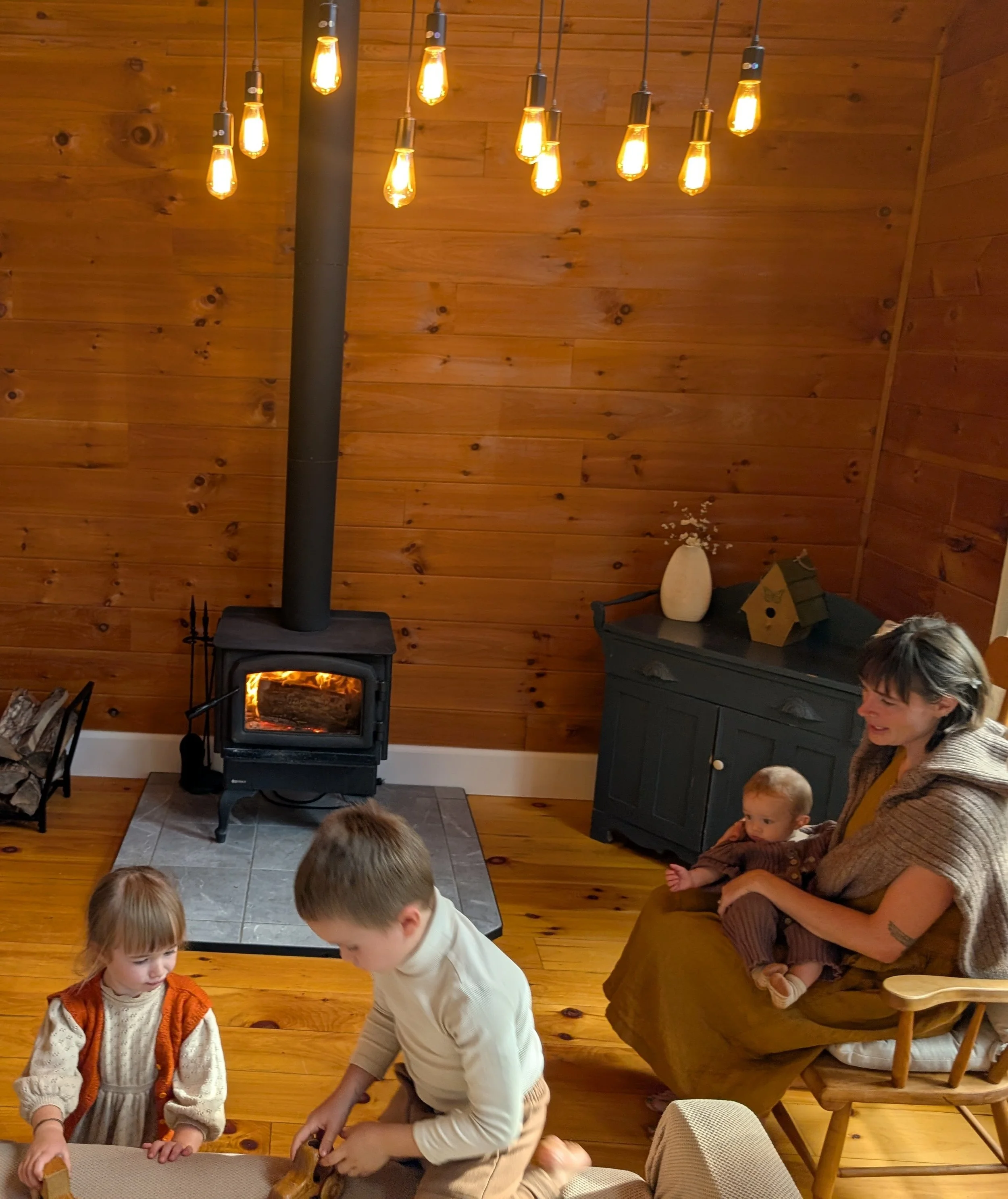 Family relaxing beside the wood-burning stove at L’Auberge des Collines in Wakefield, Quebec