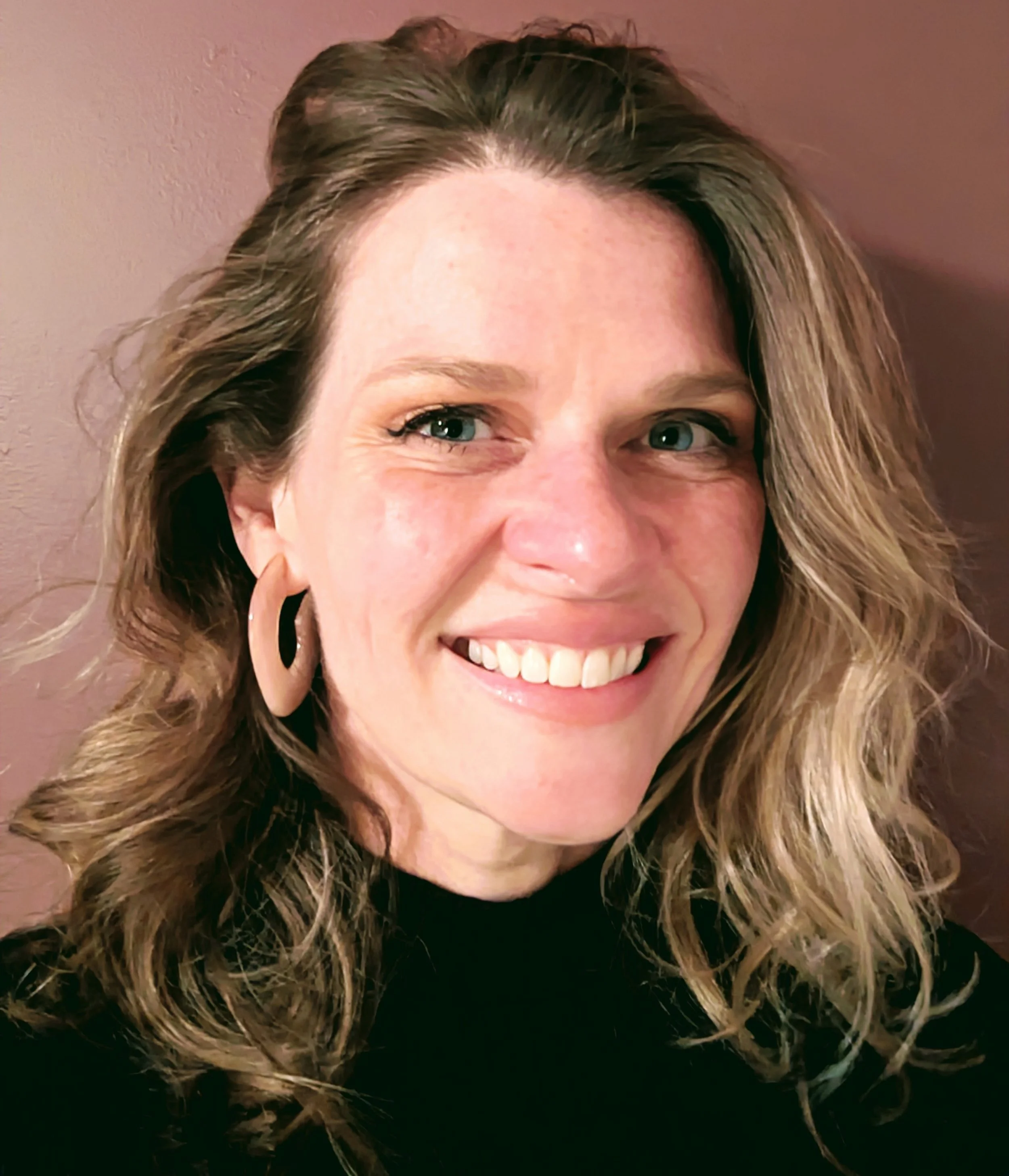 Katie Hasty of Lawrence Kansas - headshot on rose-colored background