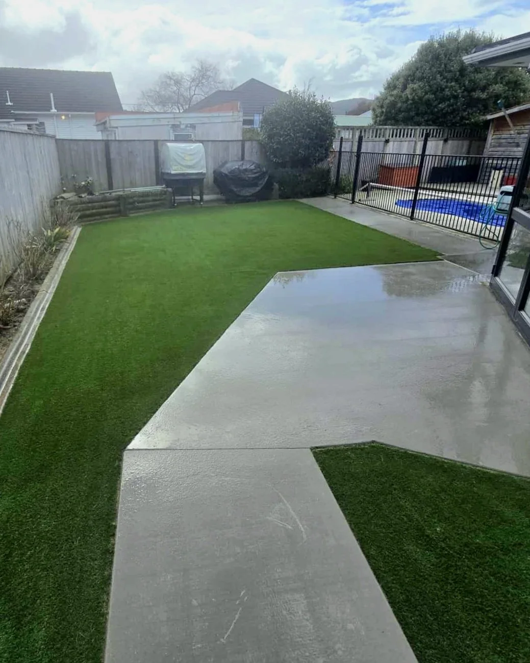 Back yard artificial turf installation at residential property with pool area and path
