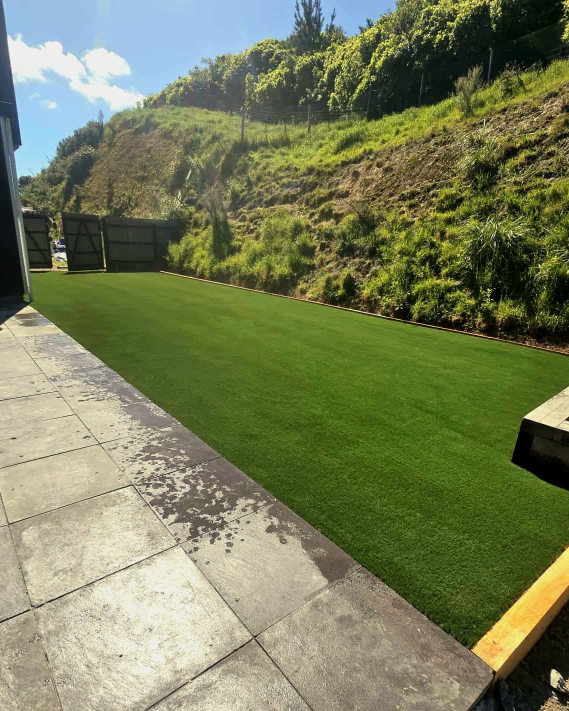 Stunning green artificial grass laid out in back lawn area with rolling green hills in background.
