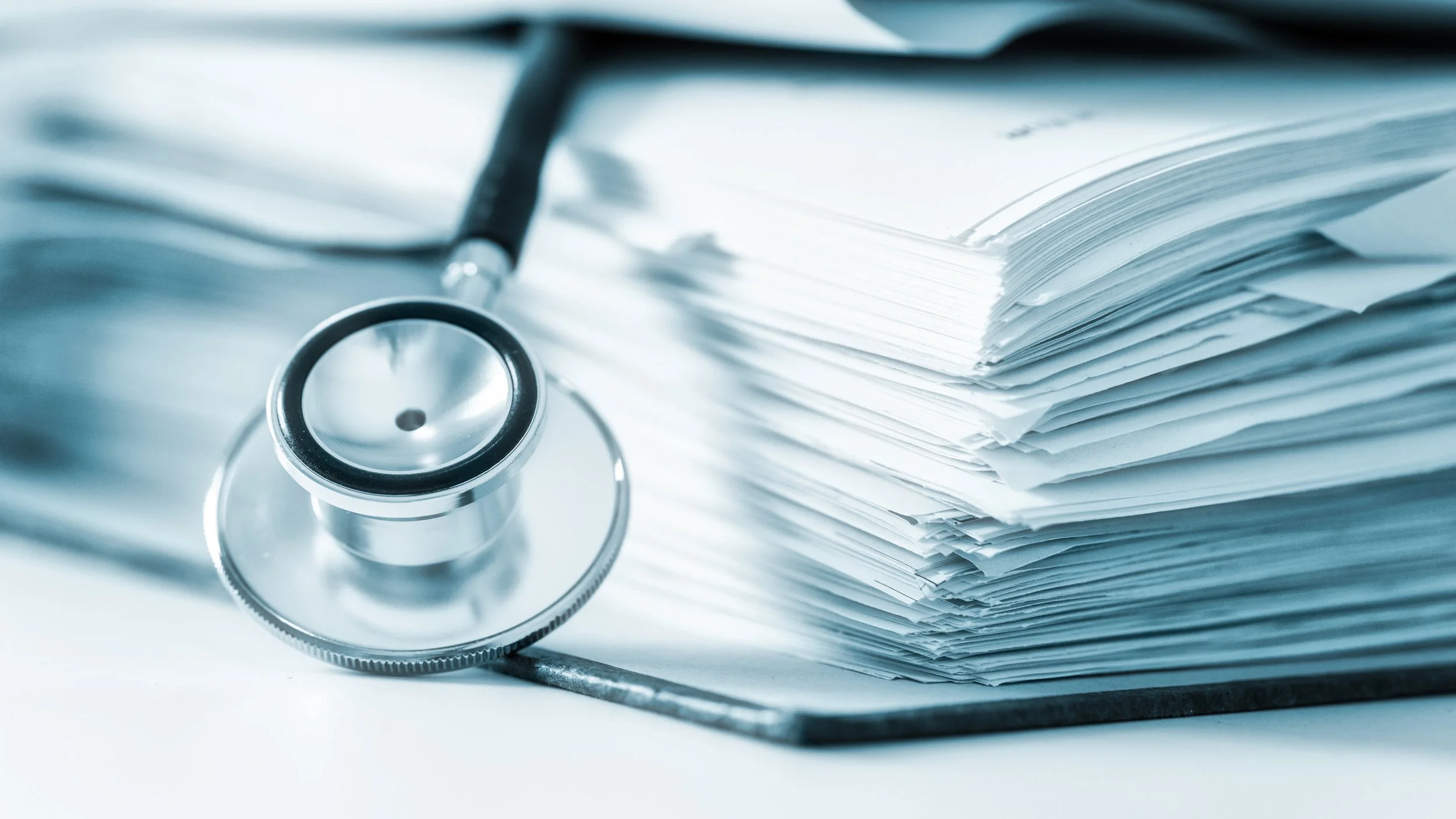 A stethoscope resting on a pile of medical papers or documents.