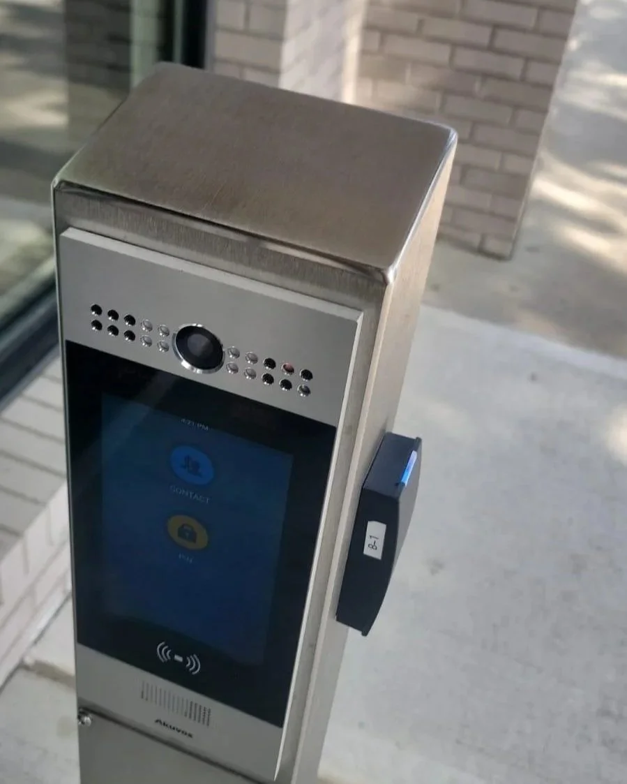 A modern contactless door entry system with a screen, camera, and card reader installed outside a building.