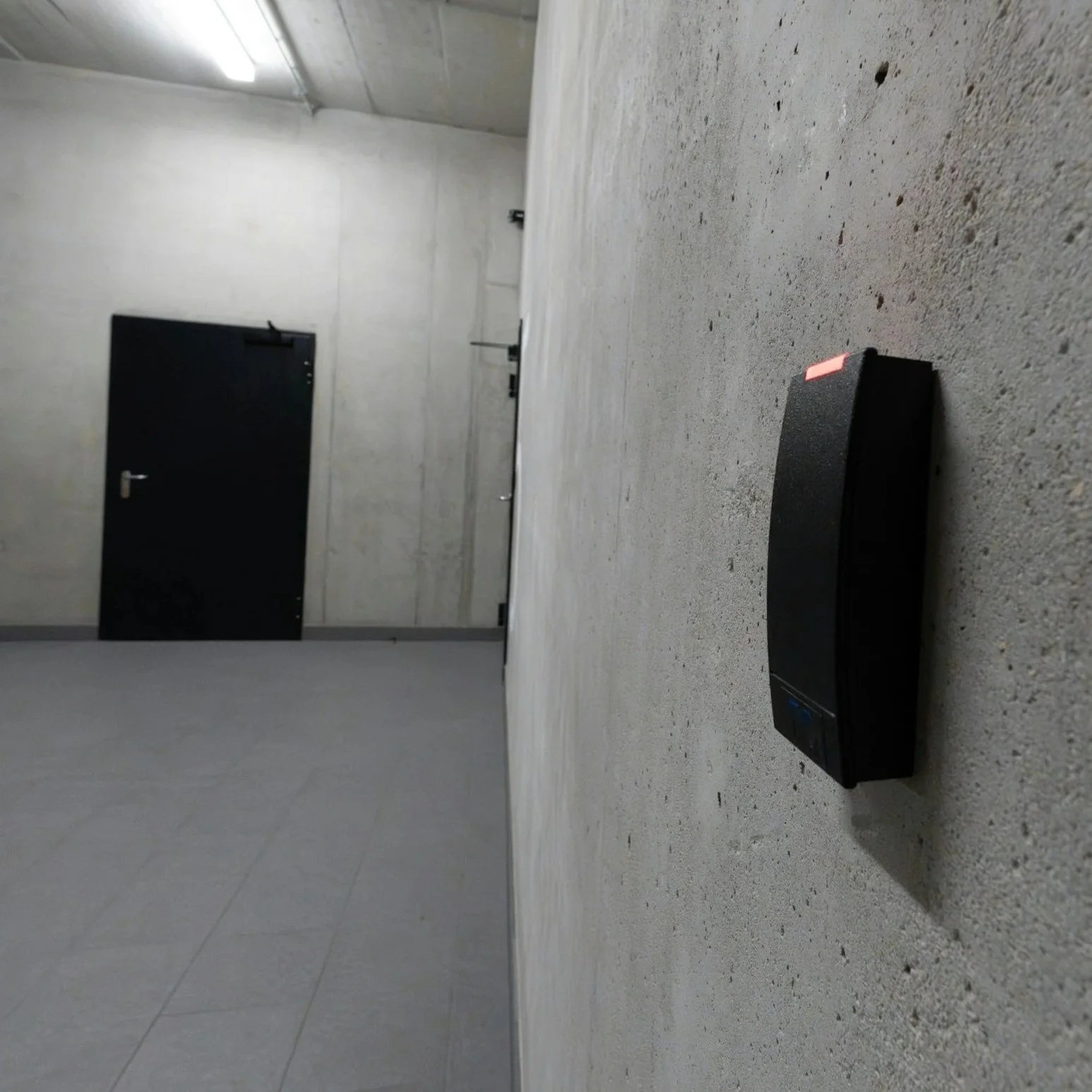 Empty underground parking garage with a black security barrier on the floor.