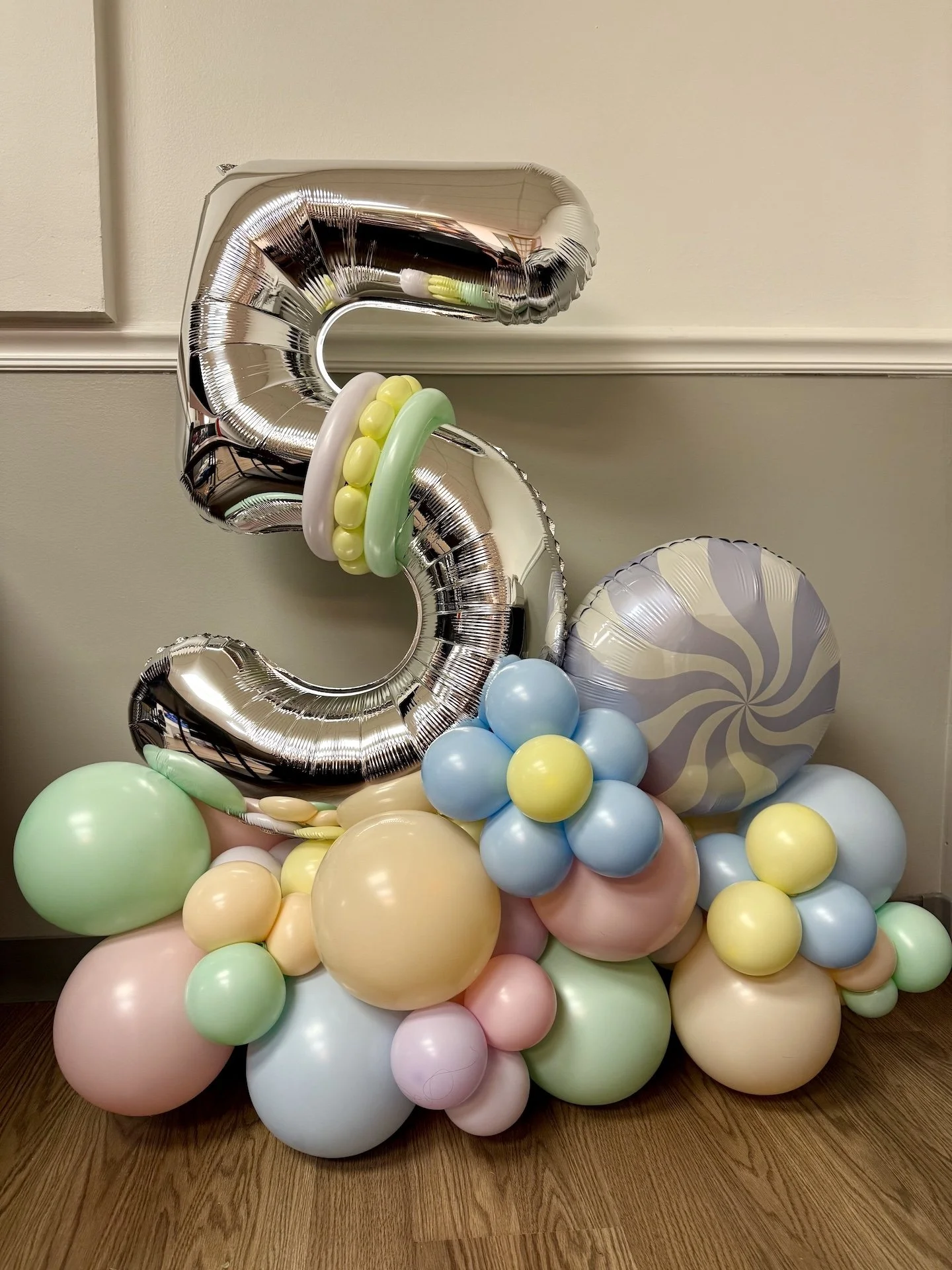 Balloon arrangement with a large silver number 3 balloon and pastel colored balloons and balloon flowers.