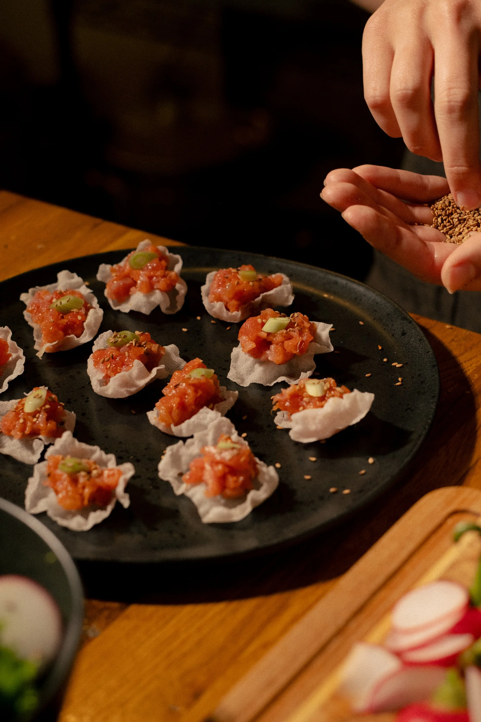 appetizer bites topped with chopped green onions, served on a black plate.