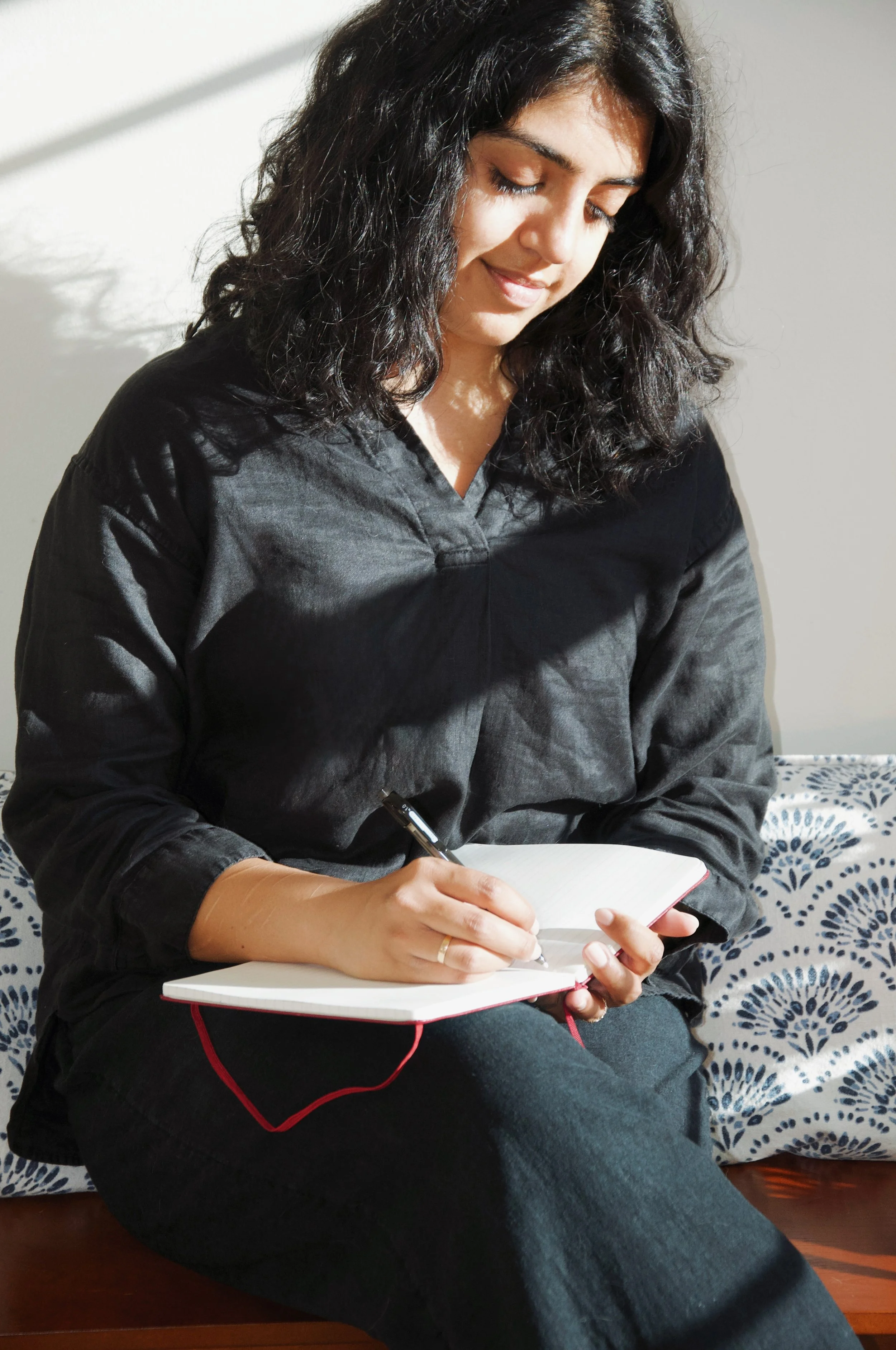 Photo of Sabah seated writing in a notebook