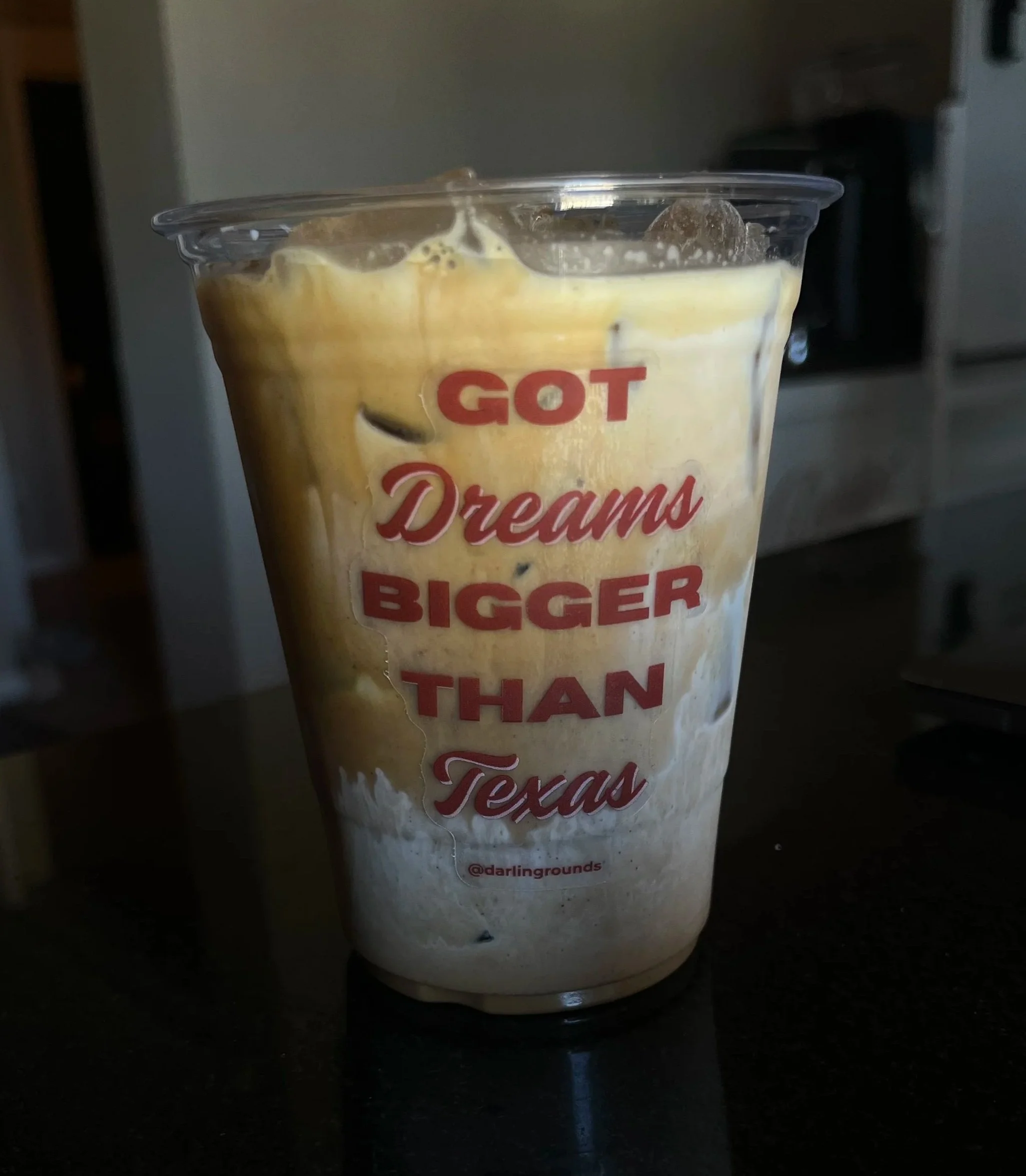 Iced specialty latte with a sticker with the words "Got Dreams Bigger Than Texas"