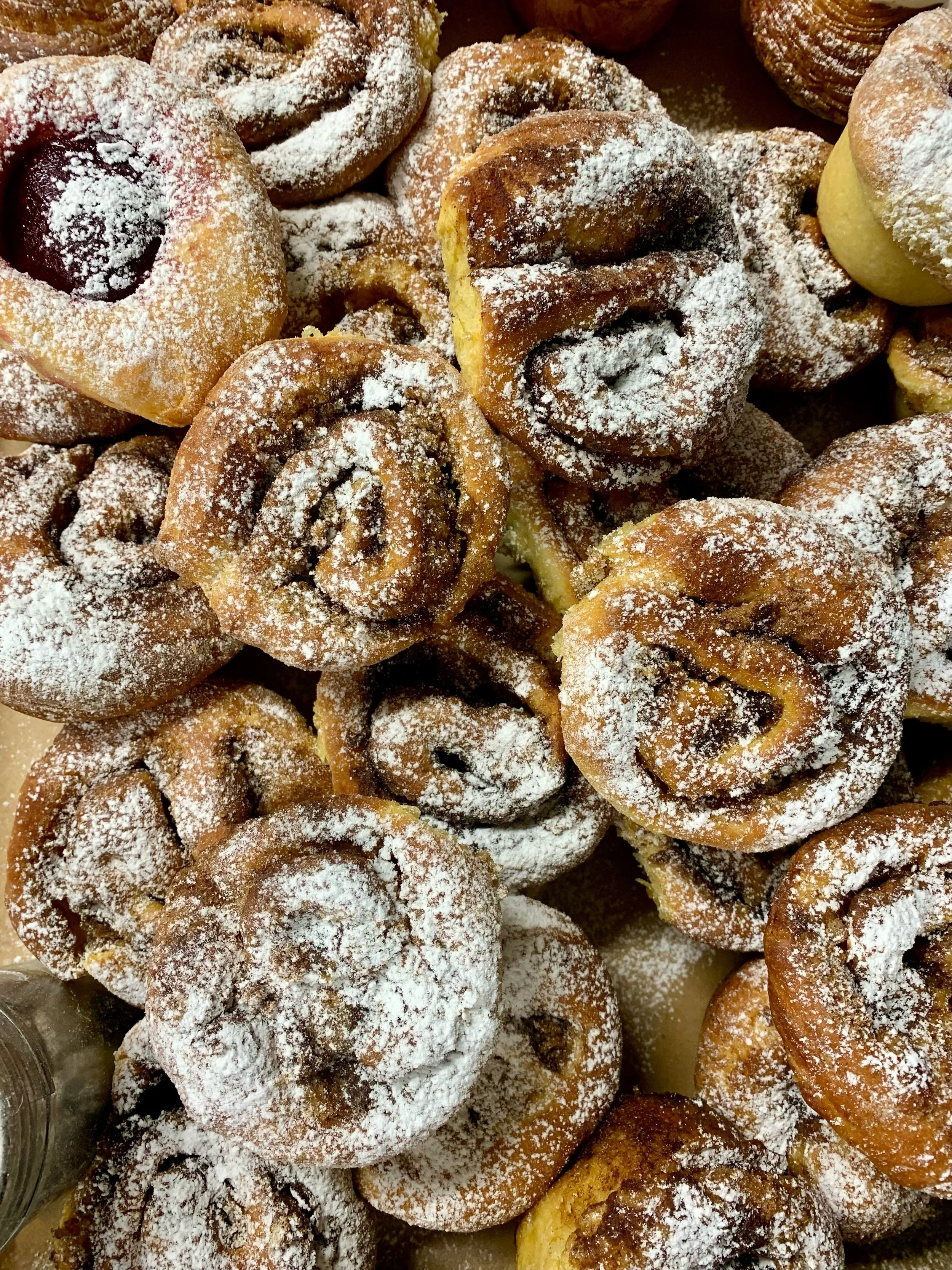 Piles of cinnamon pastries topped with powdered sugar.