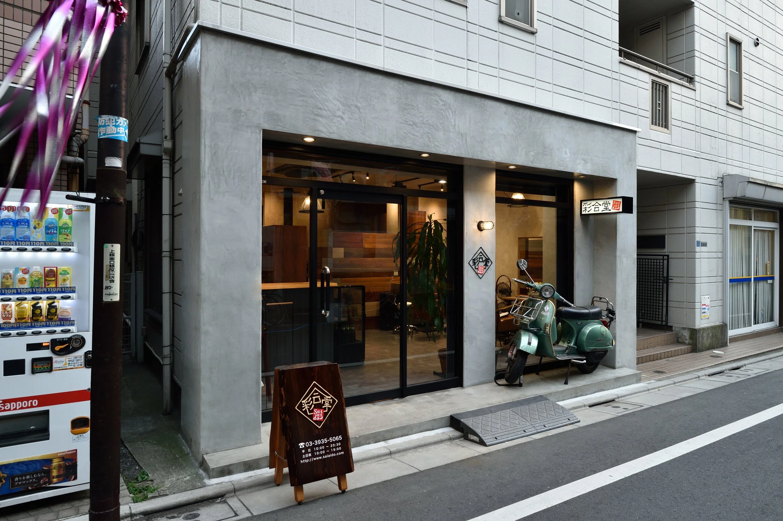 都市の通りに面したカフェの外観。ガラスの入り口とサインボードが見える。