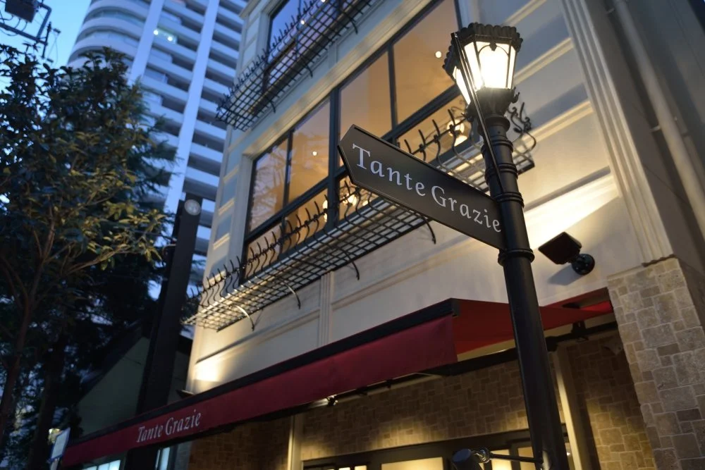 街灯と看板がある建物の外観。看板には「Tante Grazie」と書かれている。