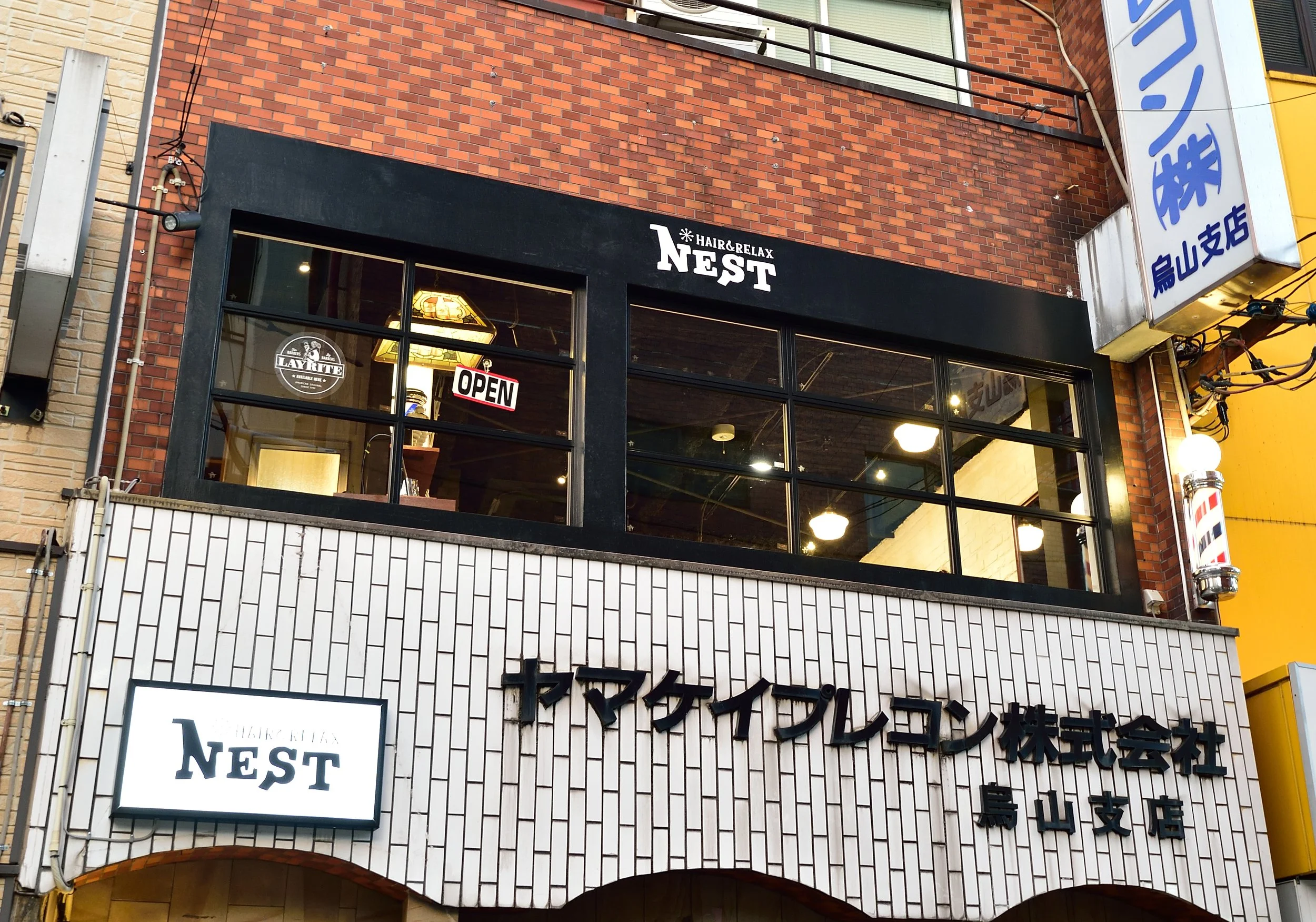 赤レンガの建物の2階にある、美容院の看板と窓、