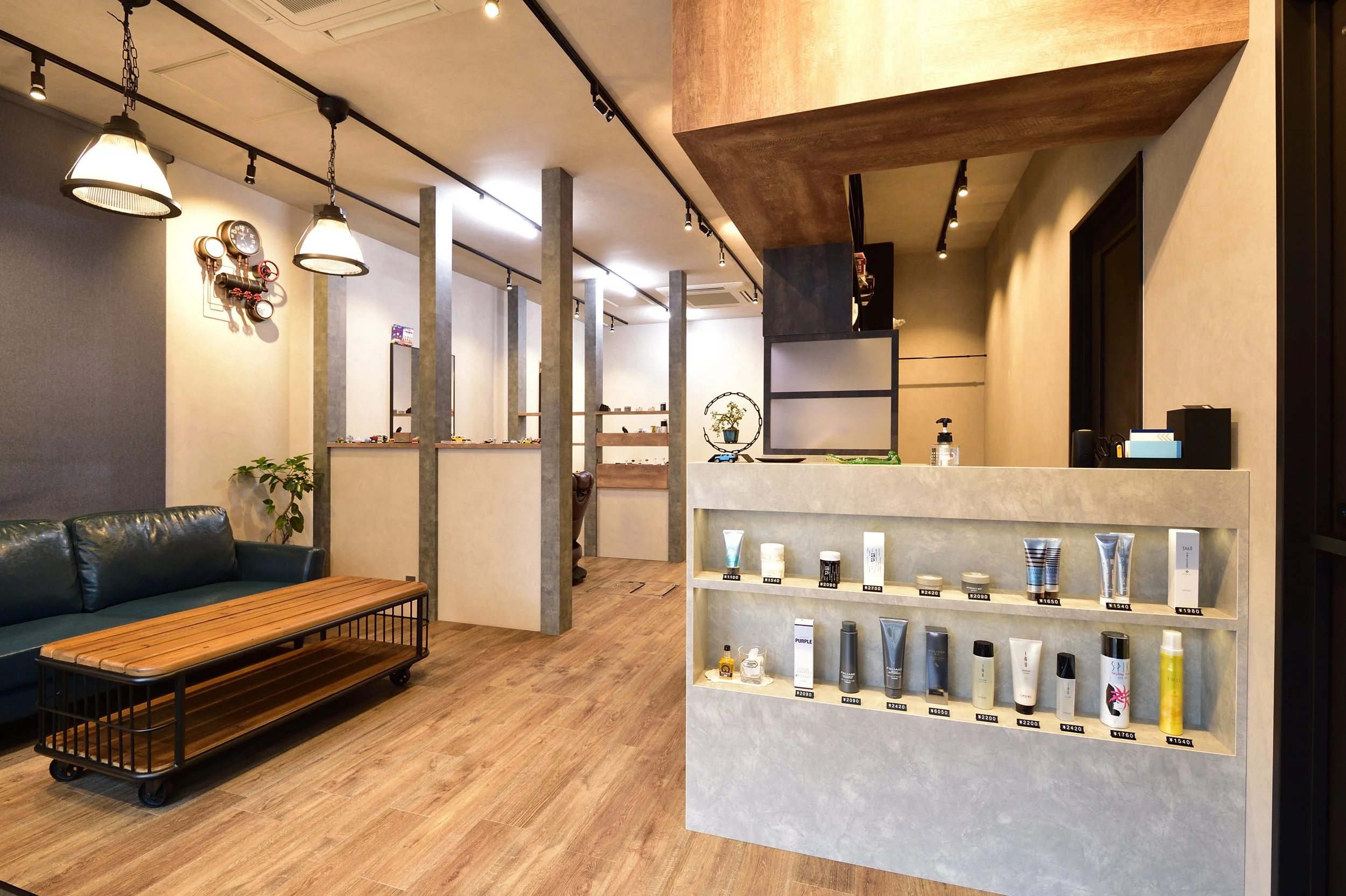 モダンなインテリアの美容院や美容サロンの店内。カウンターと商品棚、ソファ席が見える。