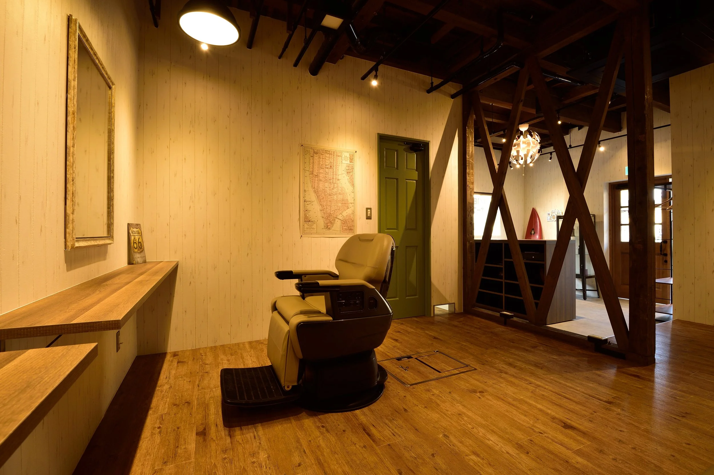 木製の床と壁の内装の部屋、緑色の扉、ソファ、壁に地図とRoute 66の看板、照明とディスプレイがあるインテリア