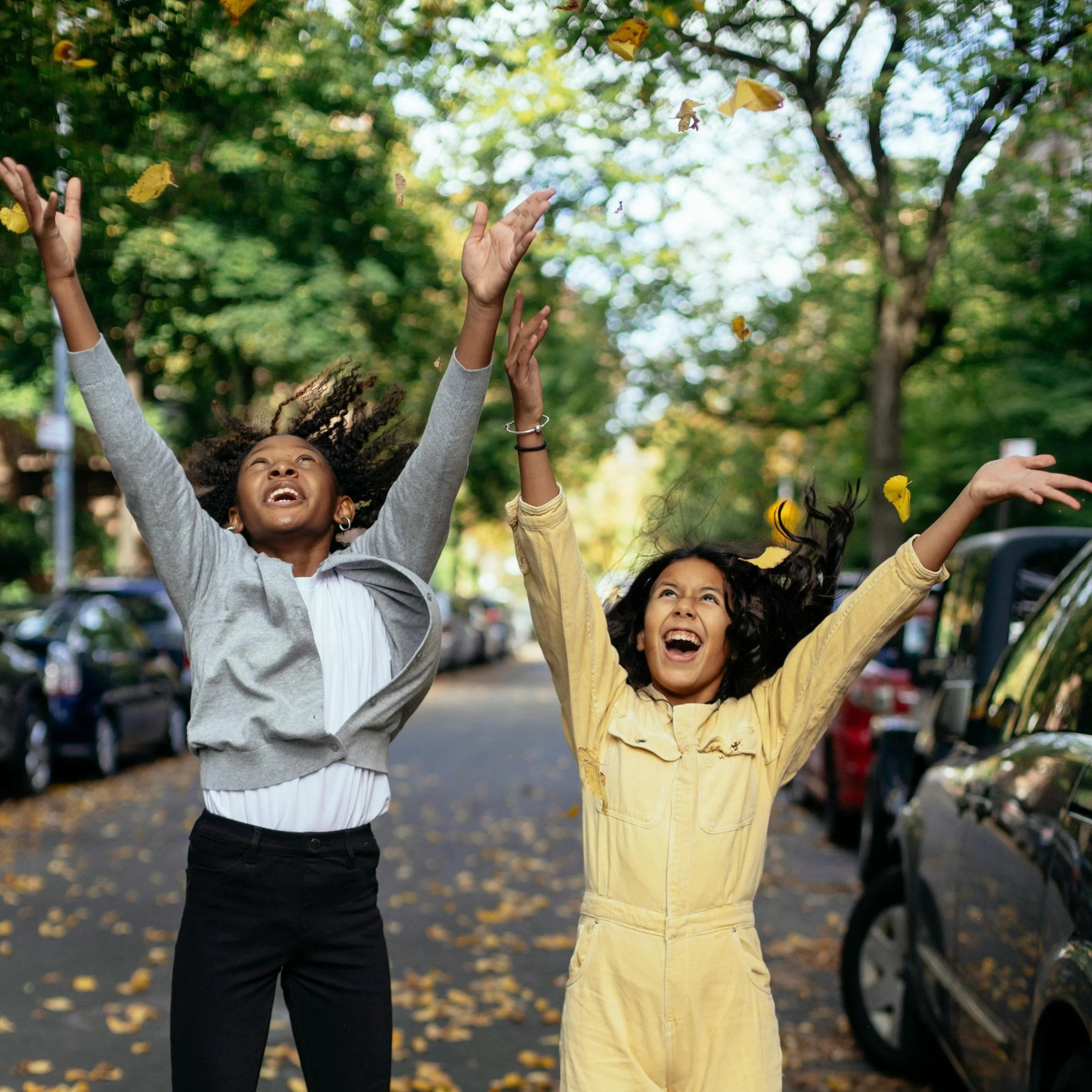 Two smiling girls jumping and cheering outside, feeling confident and free