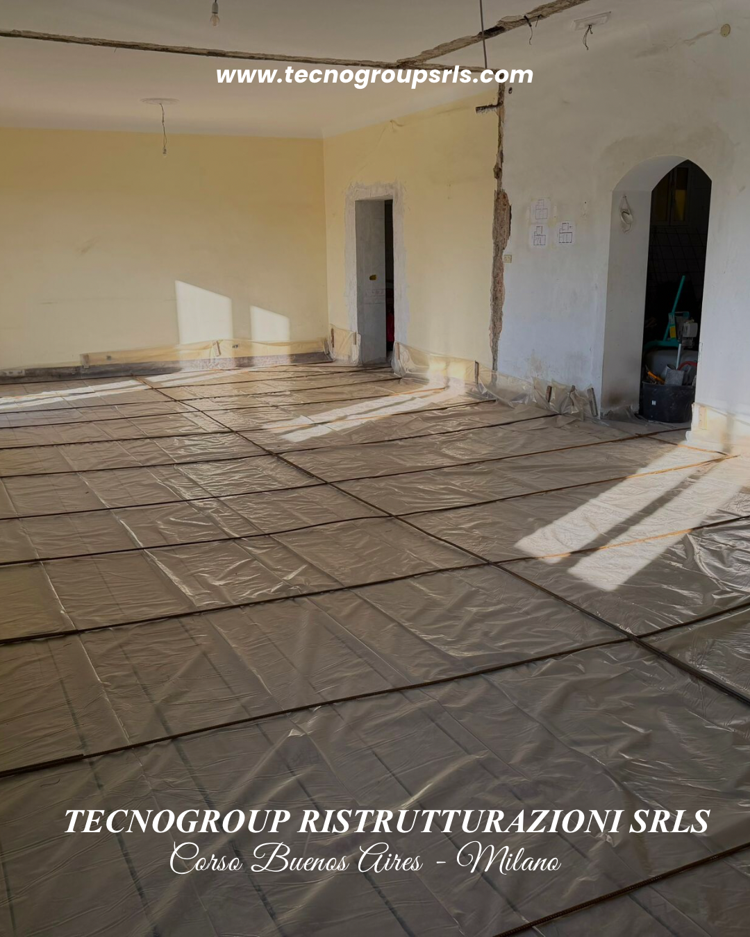 Interior room under renovation with plastic sheeting on the floor, exposed wiring along the ceiling, and partially finished walls.