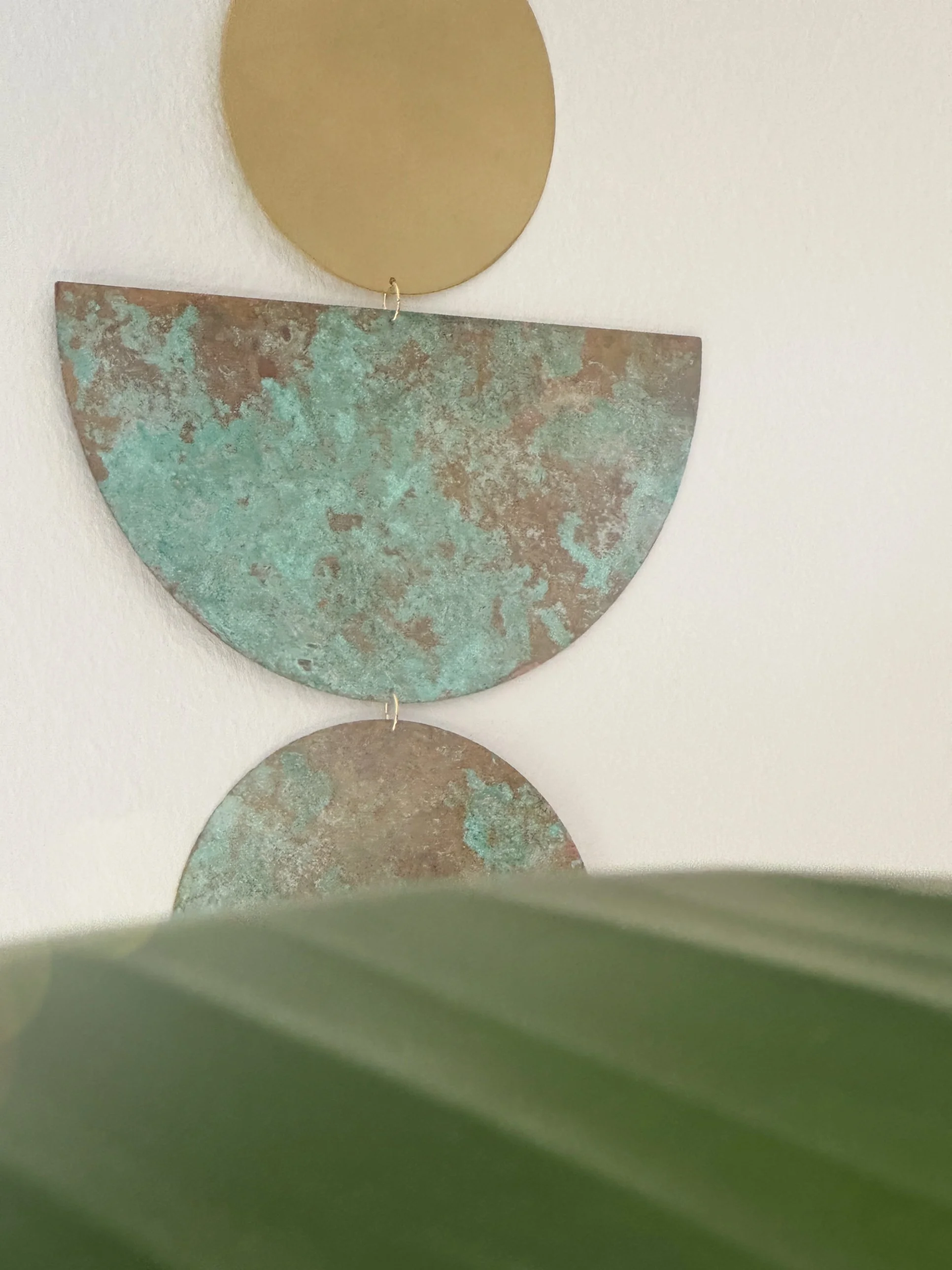 SAMAY brass patina wall hanging in a calm room with green plant, meditation decor