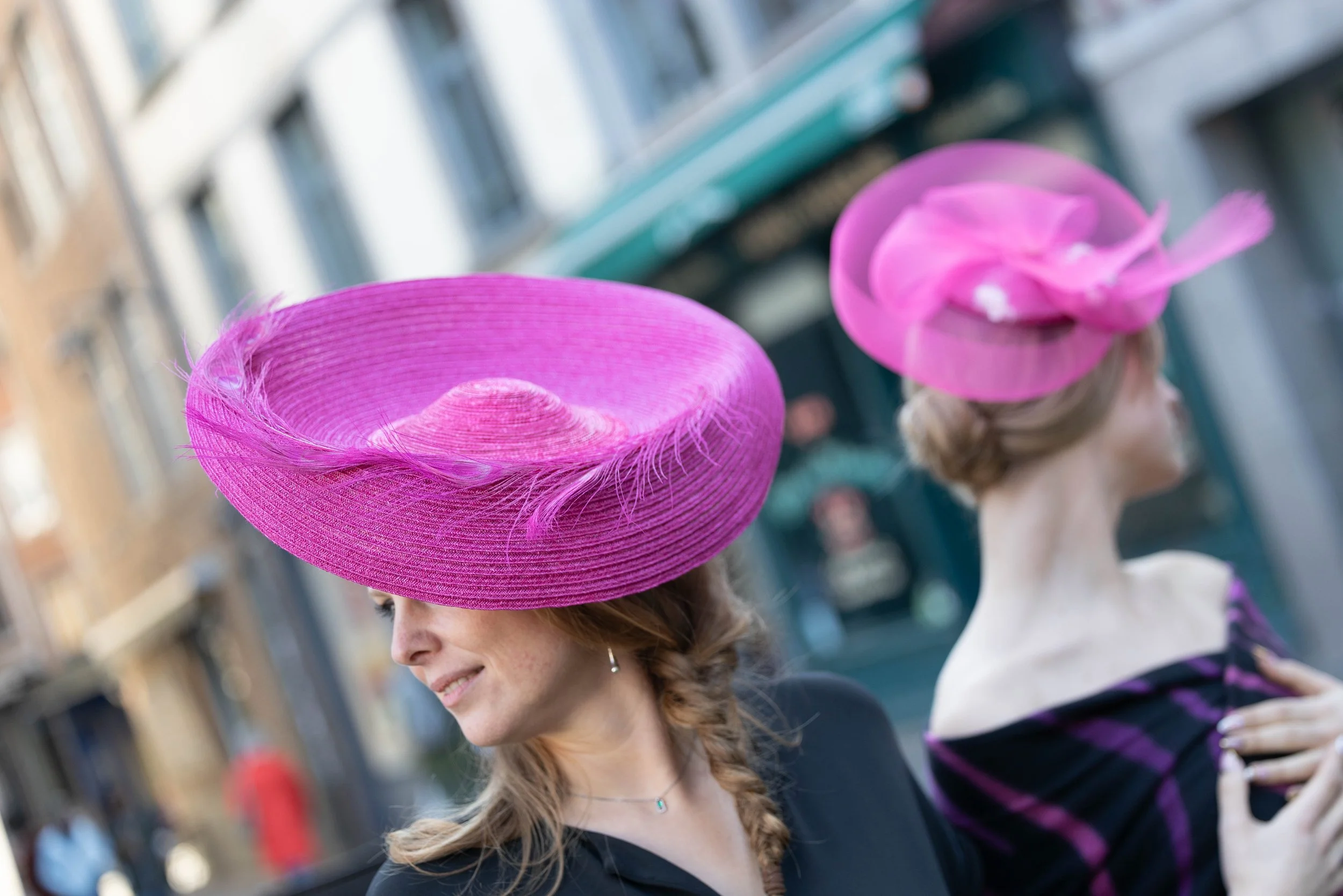 Deux femmes portent de grands chapeaux roses lors d'une réception en ville.