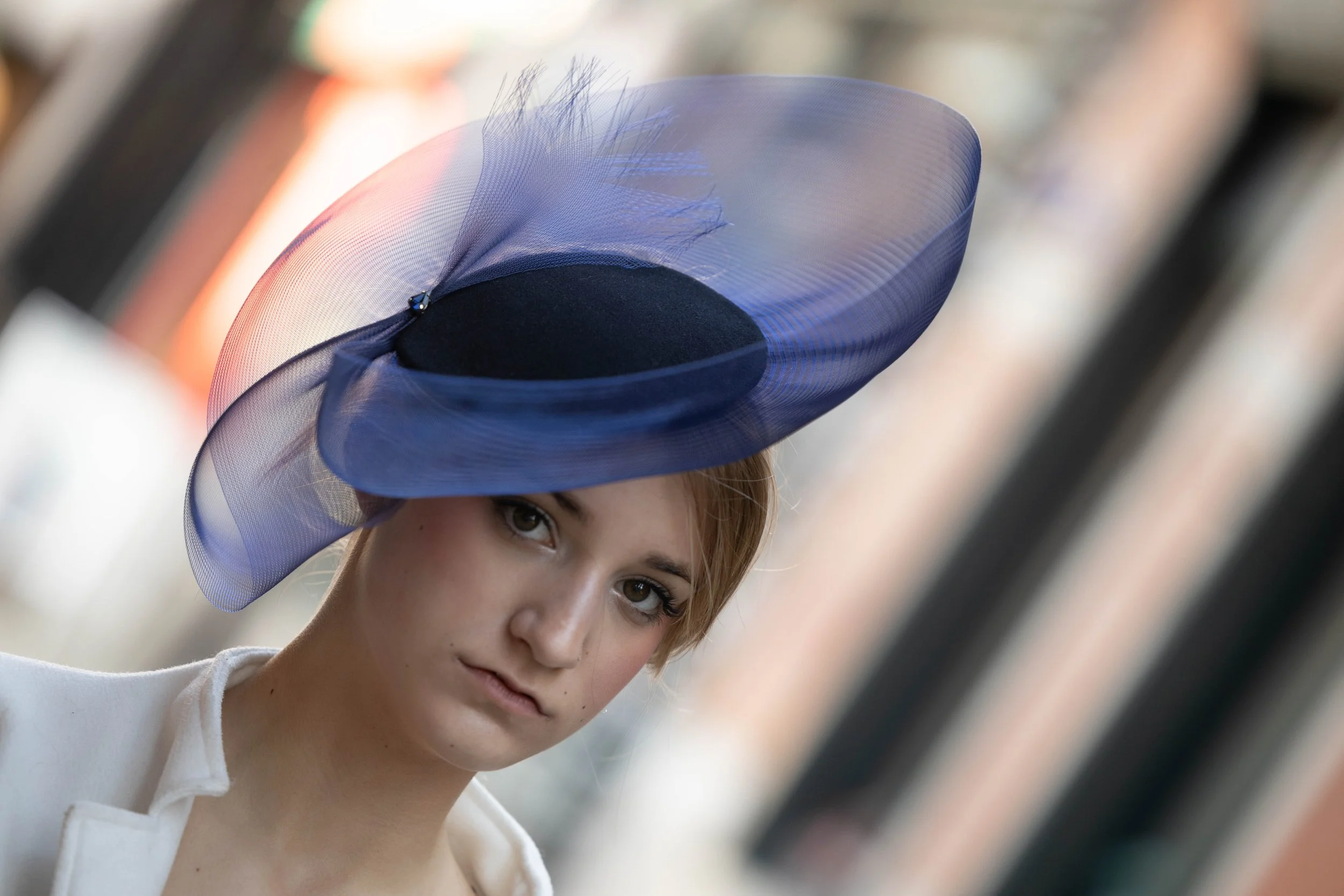 Femme portant un chapeau élégant bleu avec un voile translucide en tissu léger.