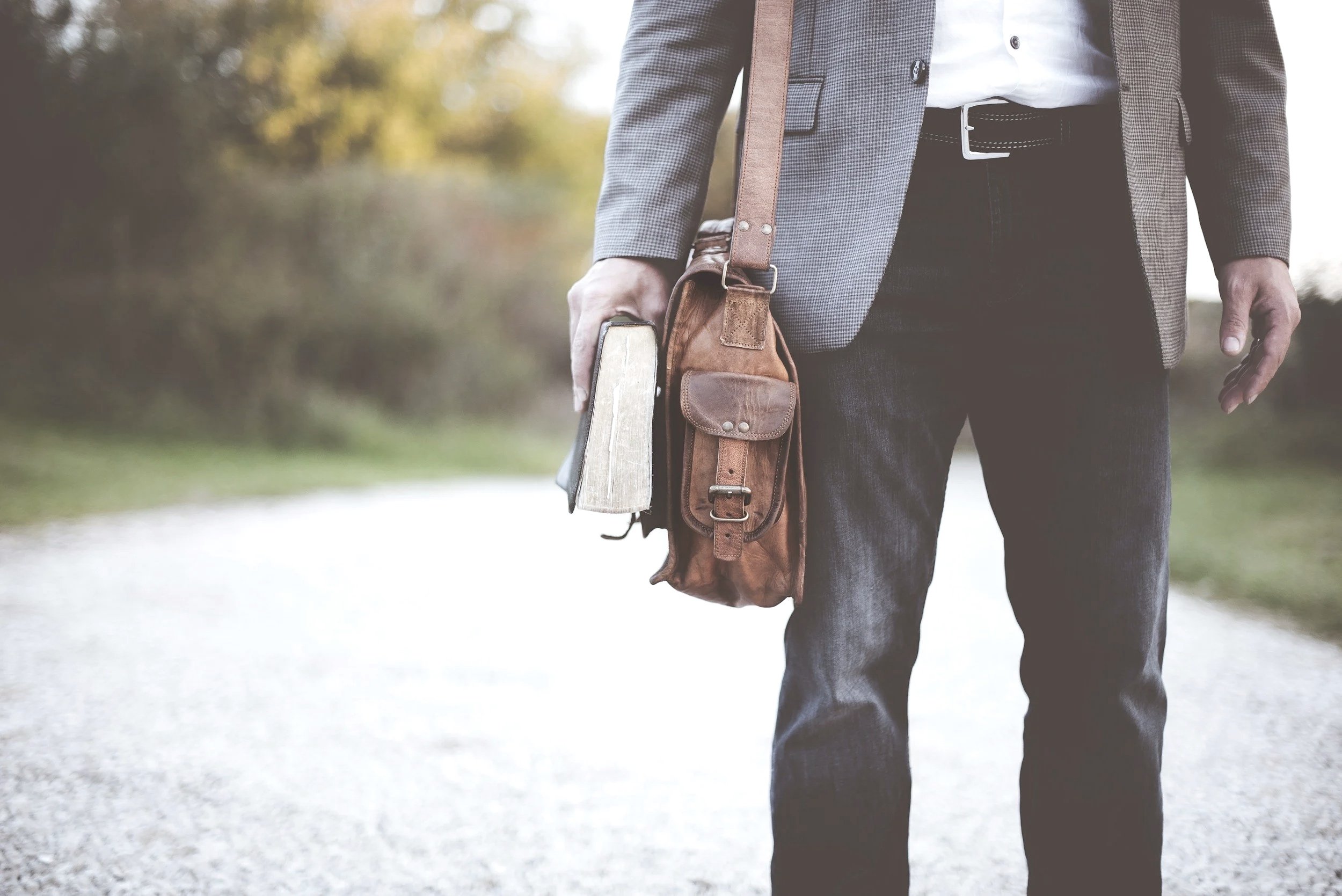 Person holding a briefcase while walking along a path, representing career coaching with Adam Print.