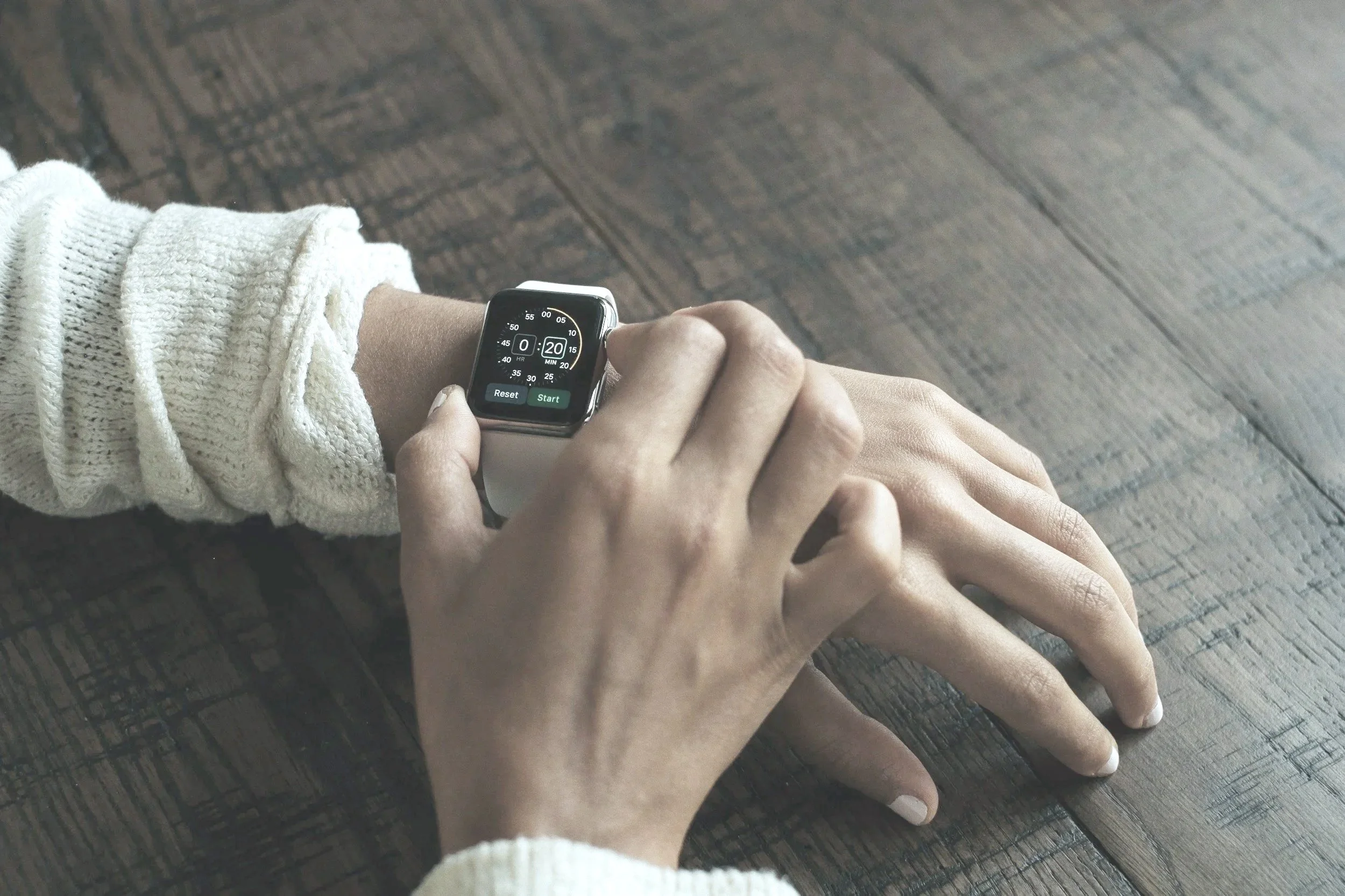 Close-up of a person adjusting a wristwatch strap, with muted tones and soft contrast.
