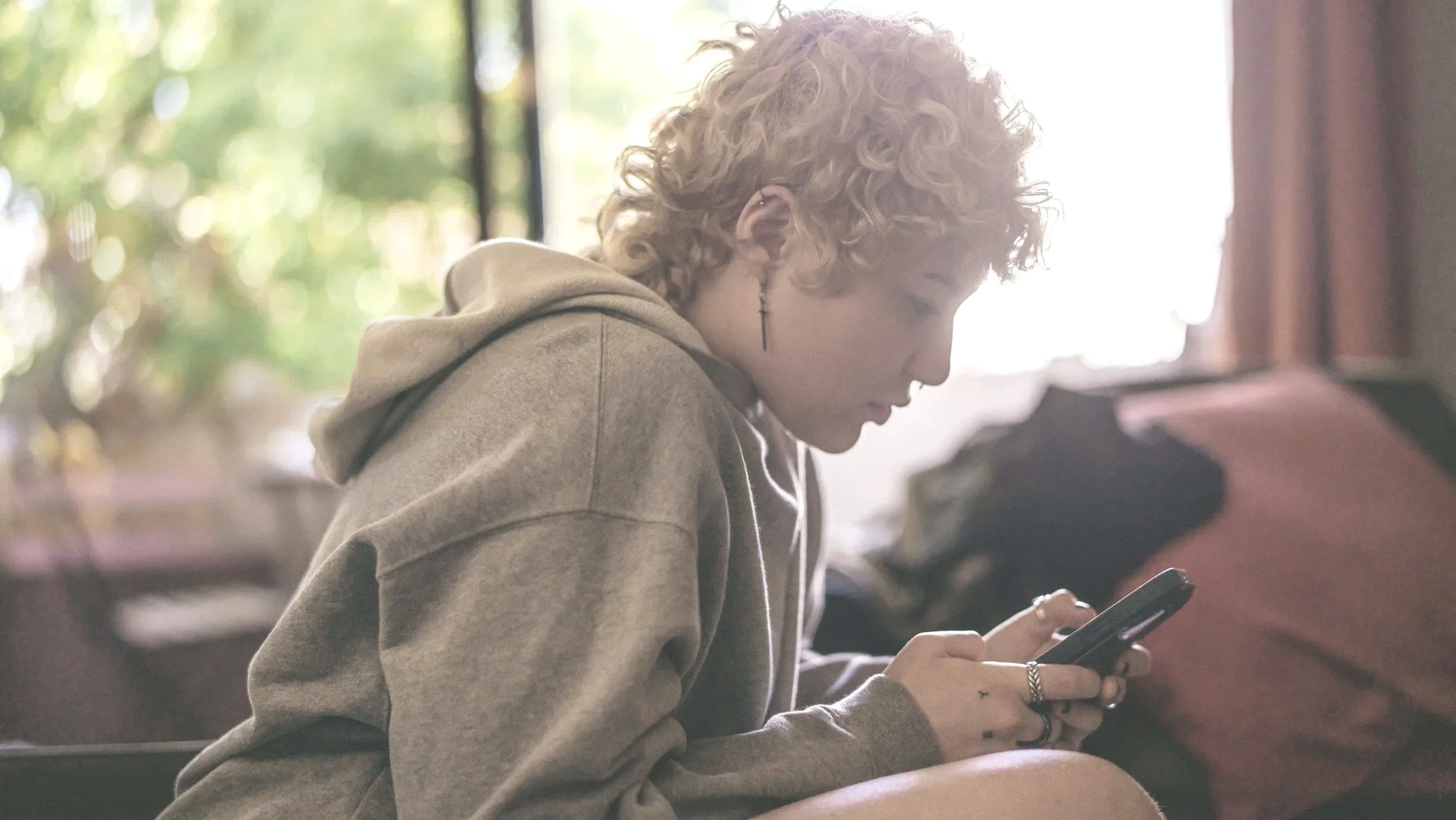Person in a hoodie sitting thoughtfully at a desk, representing focus, self-reflection, and neurodivergent experiences.