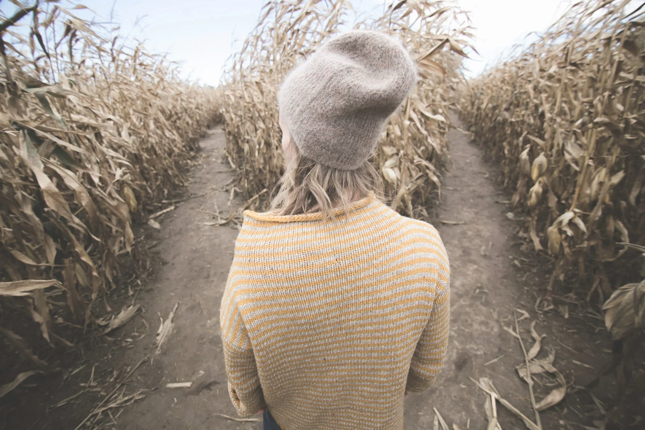 Young person standing at the entrance of a cornfield path, symbolising choice, direction, and future possibilities.