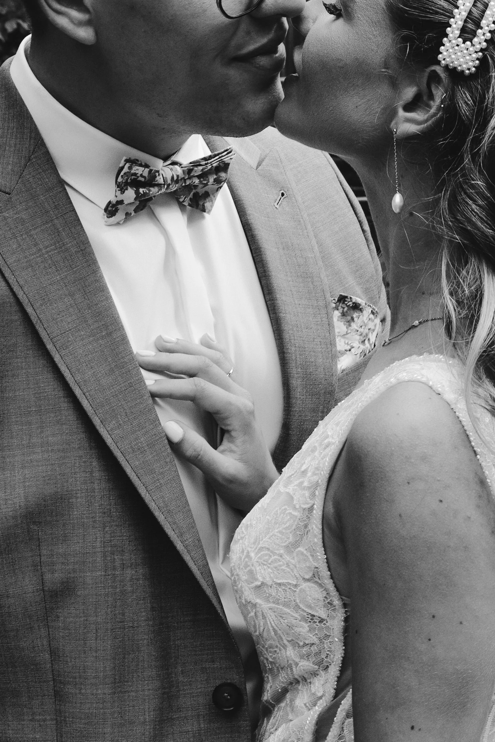 Ein Brautpaar bei einer Hochzeit, das sich küsst, in Schwarz-Weiß-Fotografie.