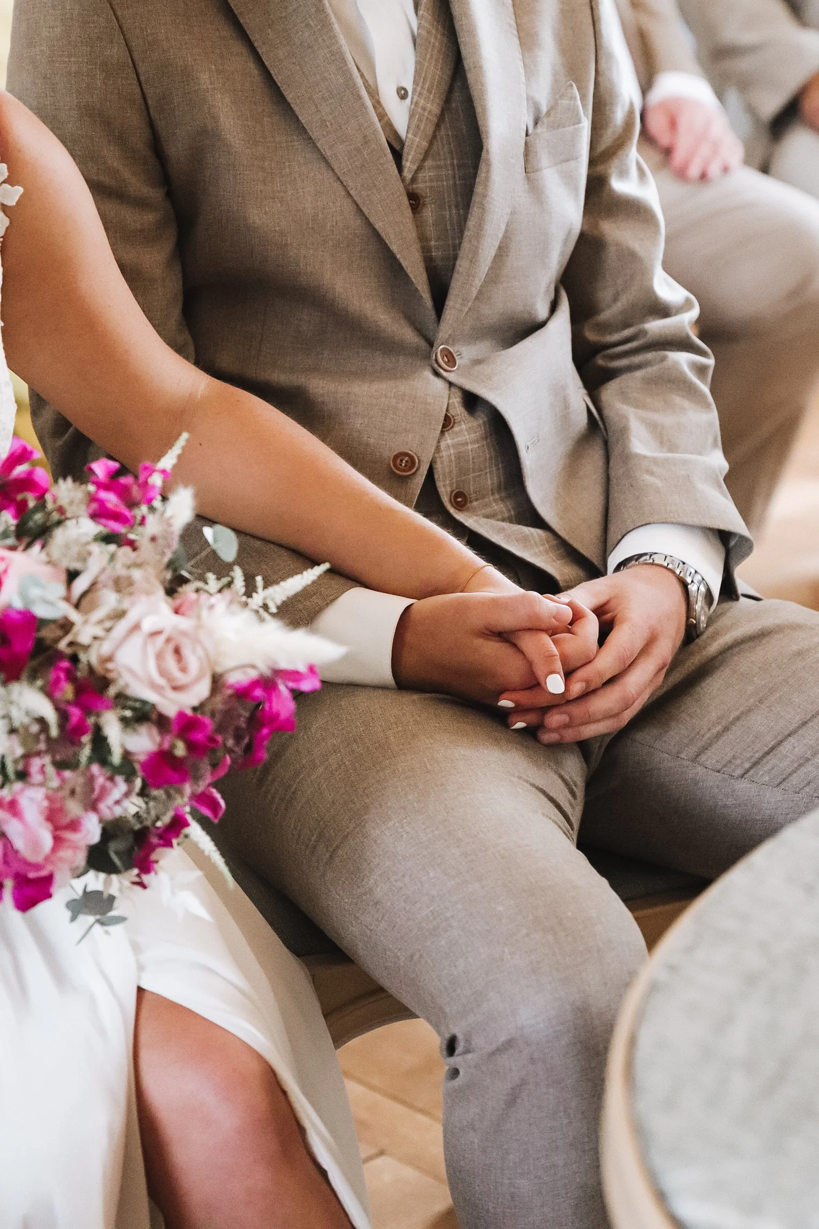 Brautpaar hält während der Trauung Händchen. 