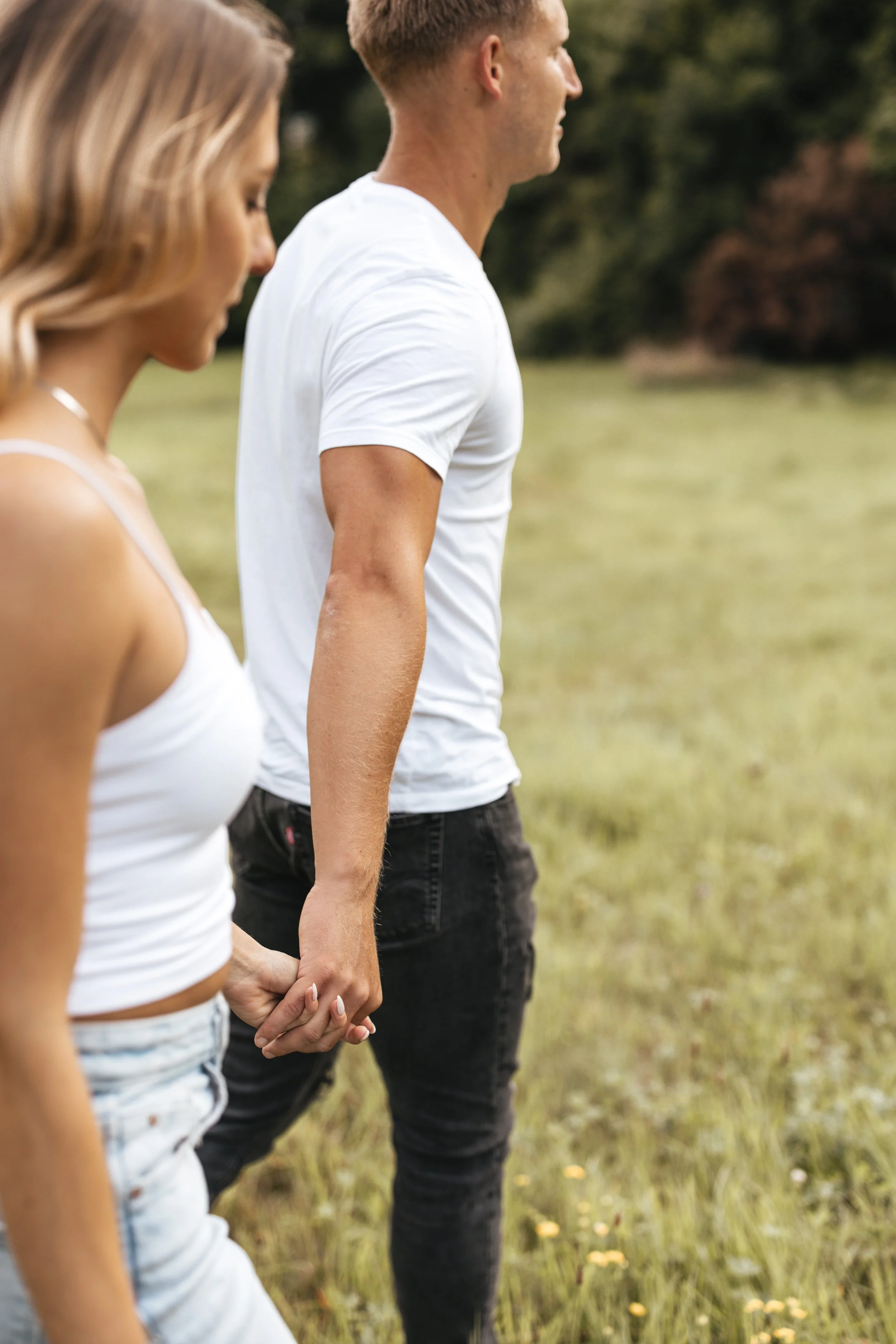 Ein Paar, das sich in einem grünen Feld die Hand hält.