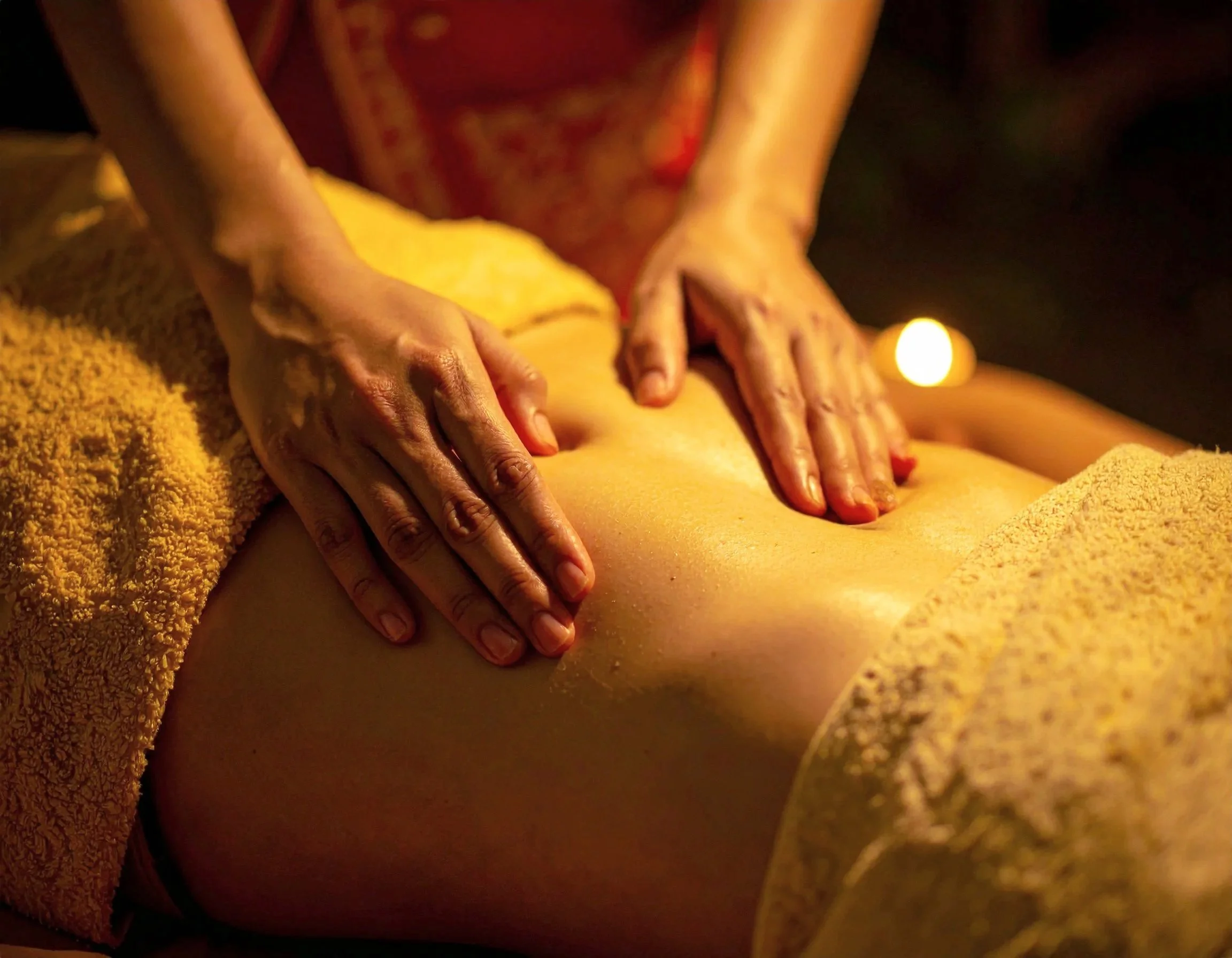 Person receiving a massage on their back in a dimly lit room.