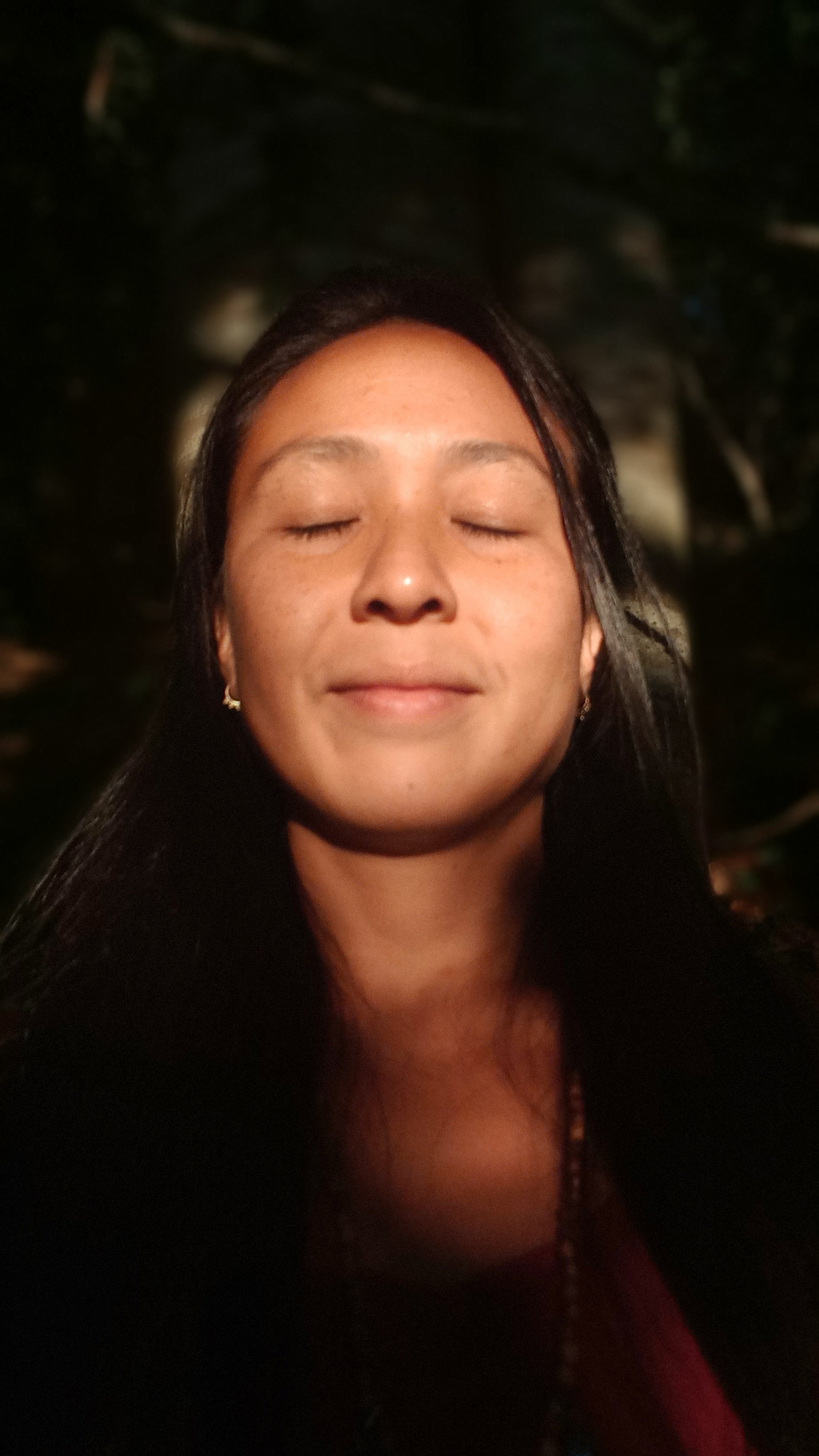Woman with closed eyes and a peaceful expression, outdoors at night.