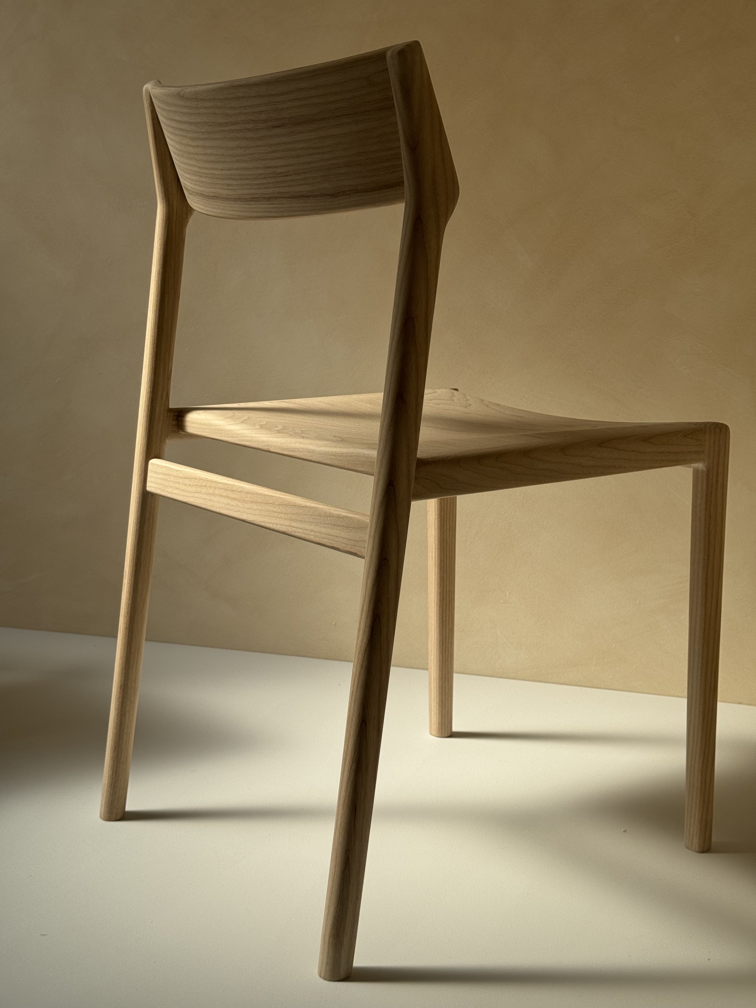 Eleven Chair by Mitch Polley Design, shown from a back angle. A contemporary dining chair with a curved backrest and scooped seat, handmade in English ash.