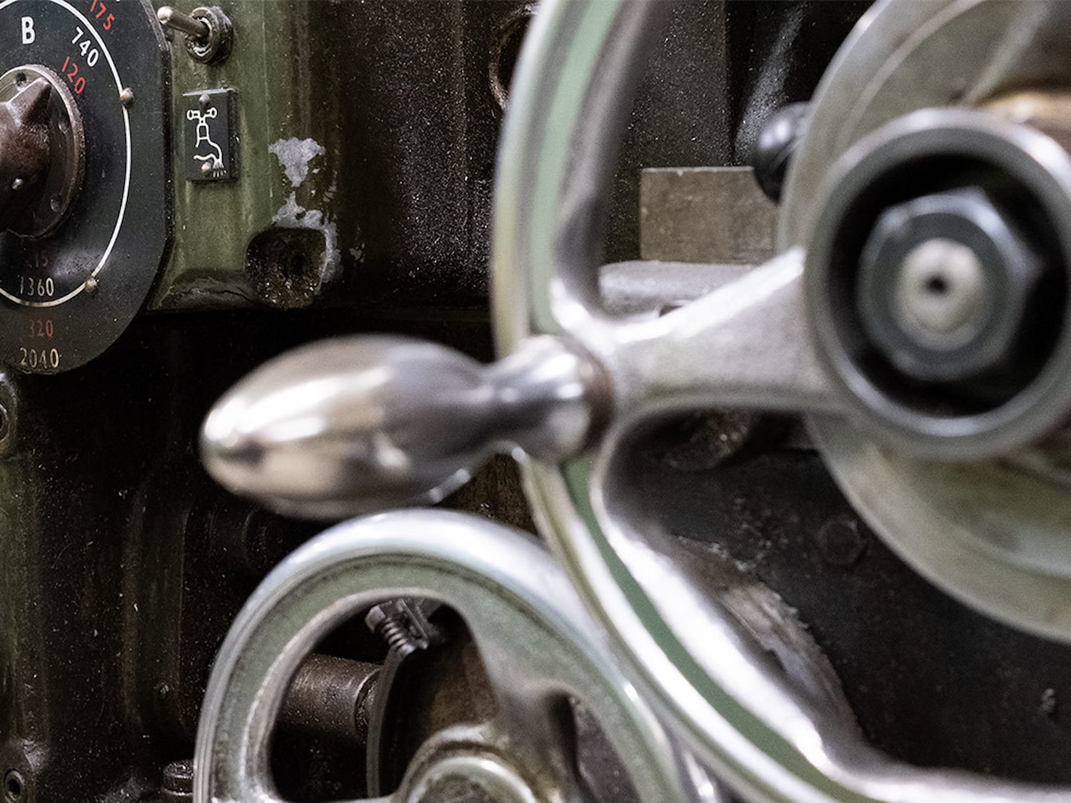 Lähikuva vanhasta metallin työstämis koneesta ohjauspyörineen.