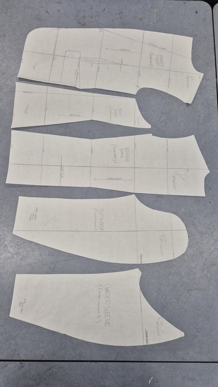 Pattern paper pieces for sewing, including sections labeled for a blazer, top, and under vest, with markings for grainline and seam allowances.