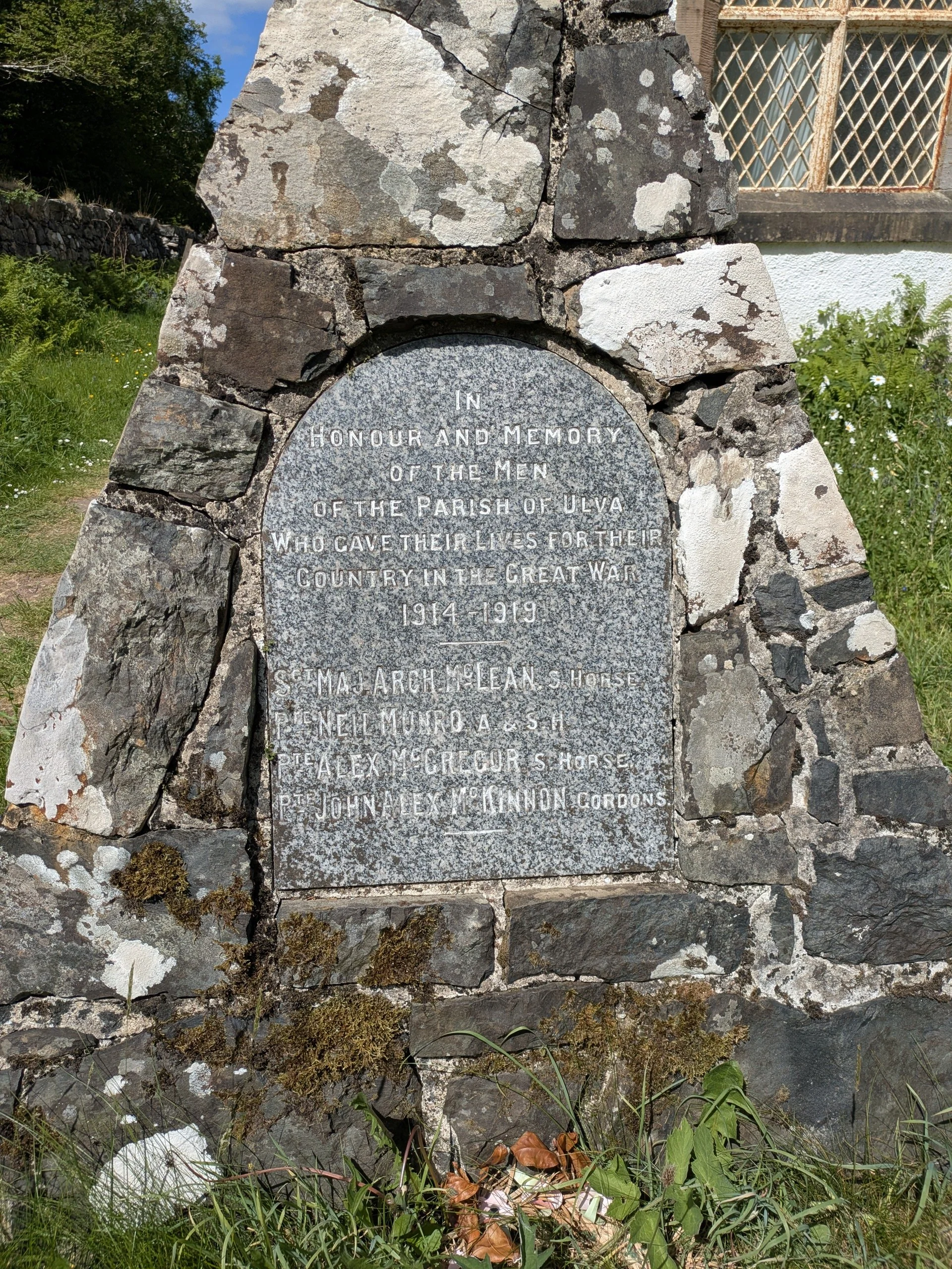 A stone memorial plaque with an inscribed message honoring men of the parish of Ulva who gave their lives in World War I, from 1914 to 1919, with names listed below the message.