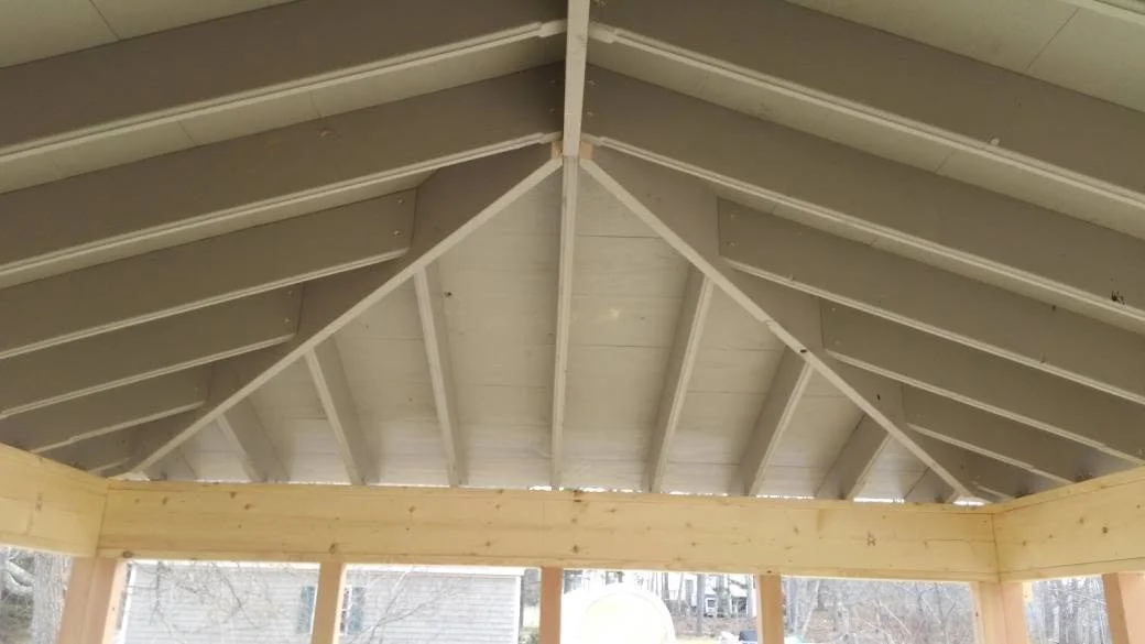 Interior view of a wooden shed or gazebo roof structure with exposed beams and rafters.