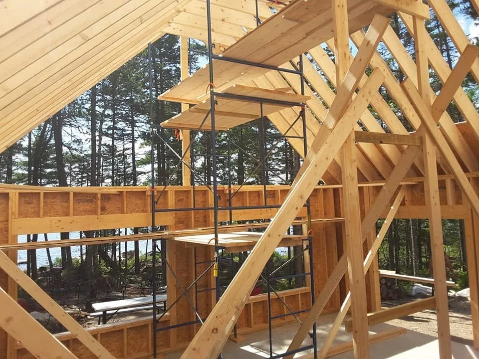 Interior view of a house under construction with wooden framing and scaffolding.