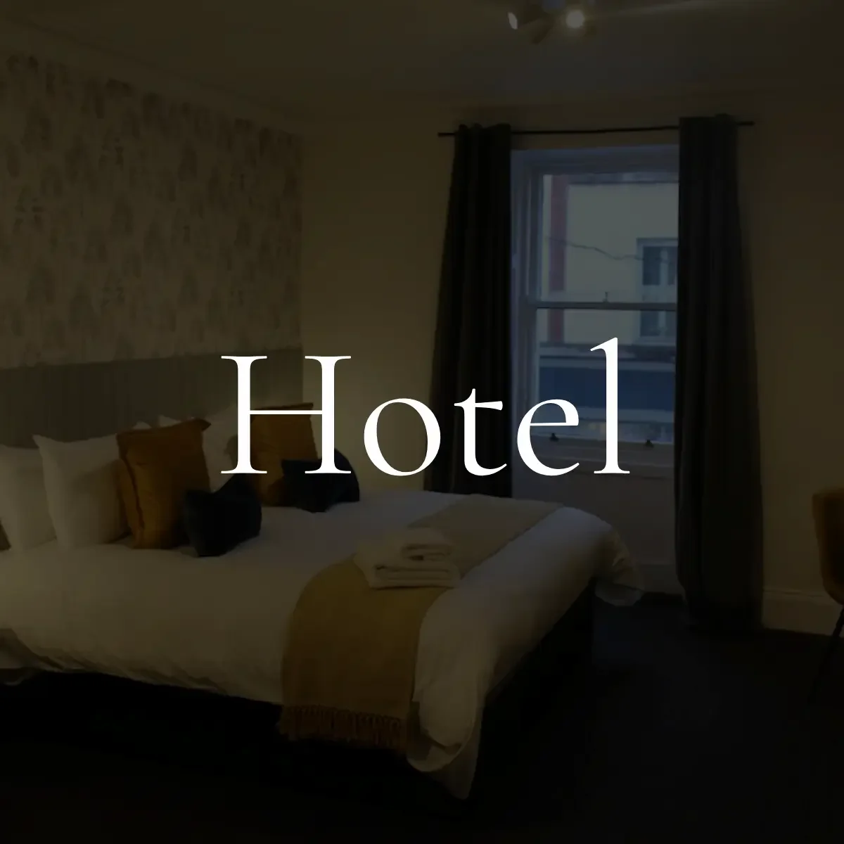 A hotel room with a bed, pillows, and a window with dark curtains, with the word 'Hotel' overlaid.