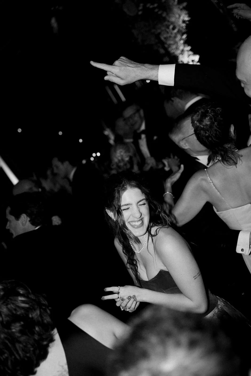 People dancing at a celebration or party at night, with a woman smiling and laughing in the foreground.