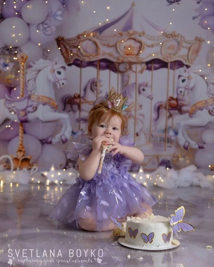 Girl celebrating her birthday in a purple carousel-themed portrait session.
