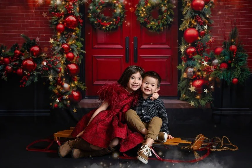 Brother and sister posing together on a Christmas sled during a holiday photography session in West Windsor, NJ.
