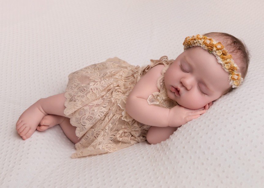 Newborn portrait session capturing the delicate beauty of a baby’s first days with soft blankets and gentle posing.