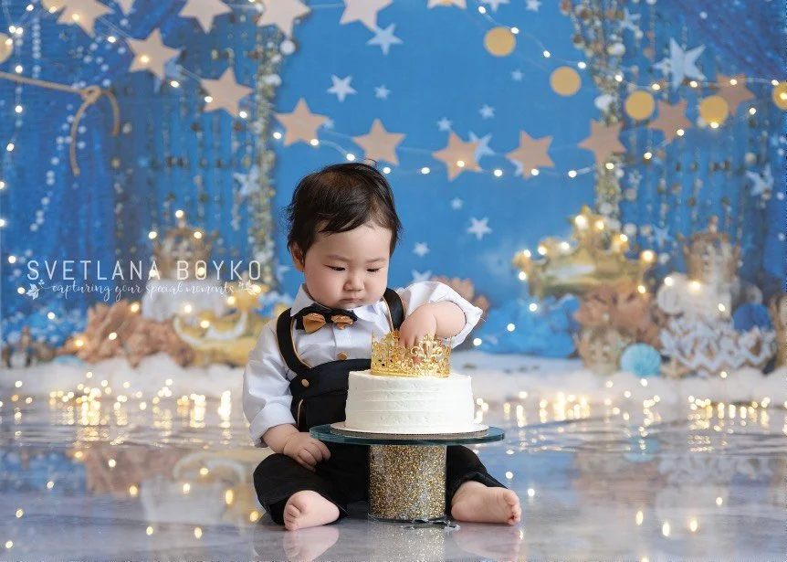 Baby boy reaching for his cake during a blue celestial cake smash