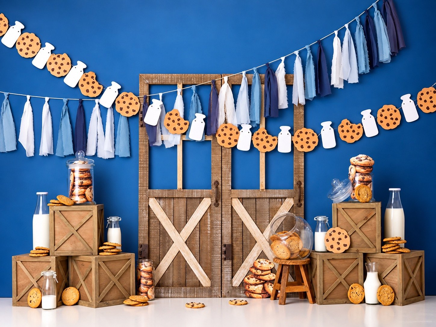 Milk and cookies cake smash backdrop featuring blue and white décor, rustic wooden doors, cookies, milk bottles, and wooden crates. Available for first birthday cake smash sessions at our West Windsor, NJ photography studio near Princeton.