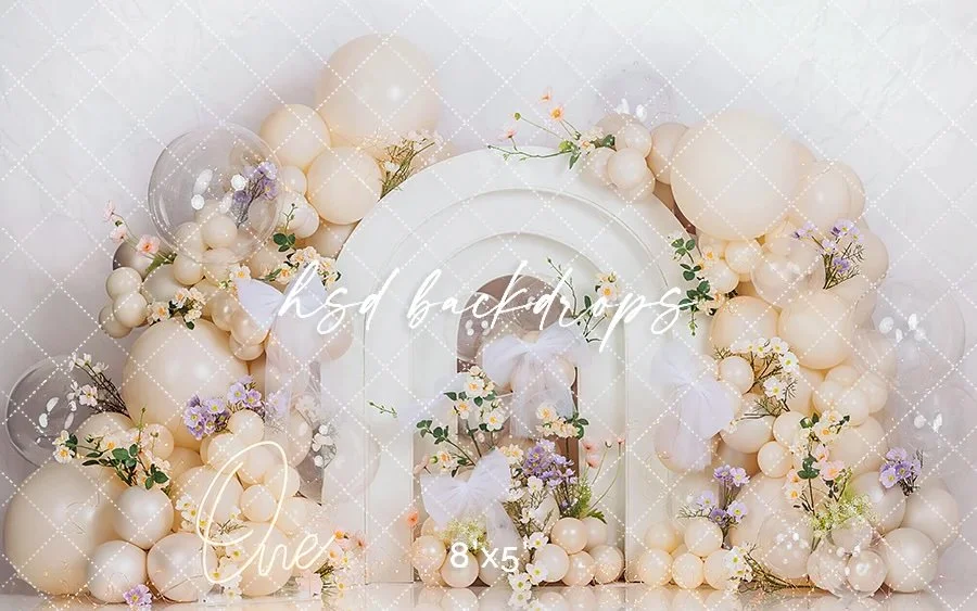 Decorative floral display with cream-colored balloons, white butterflies, and small purple and pink flowers arranged around a white background.