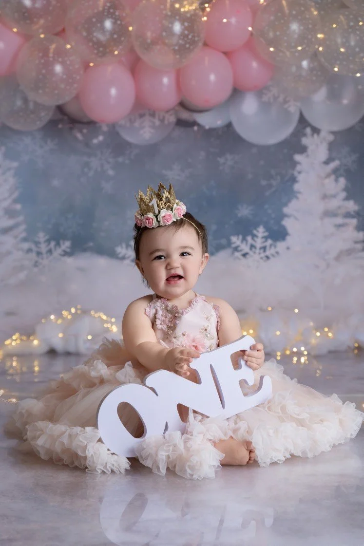 Baby enjoying a first birthday cake smash session with a football-themed setup in a Mercer County NJ studio