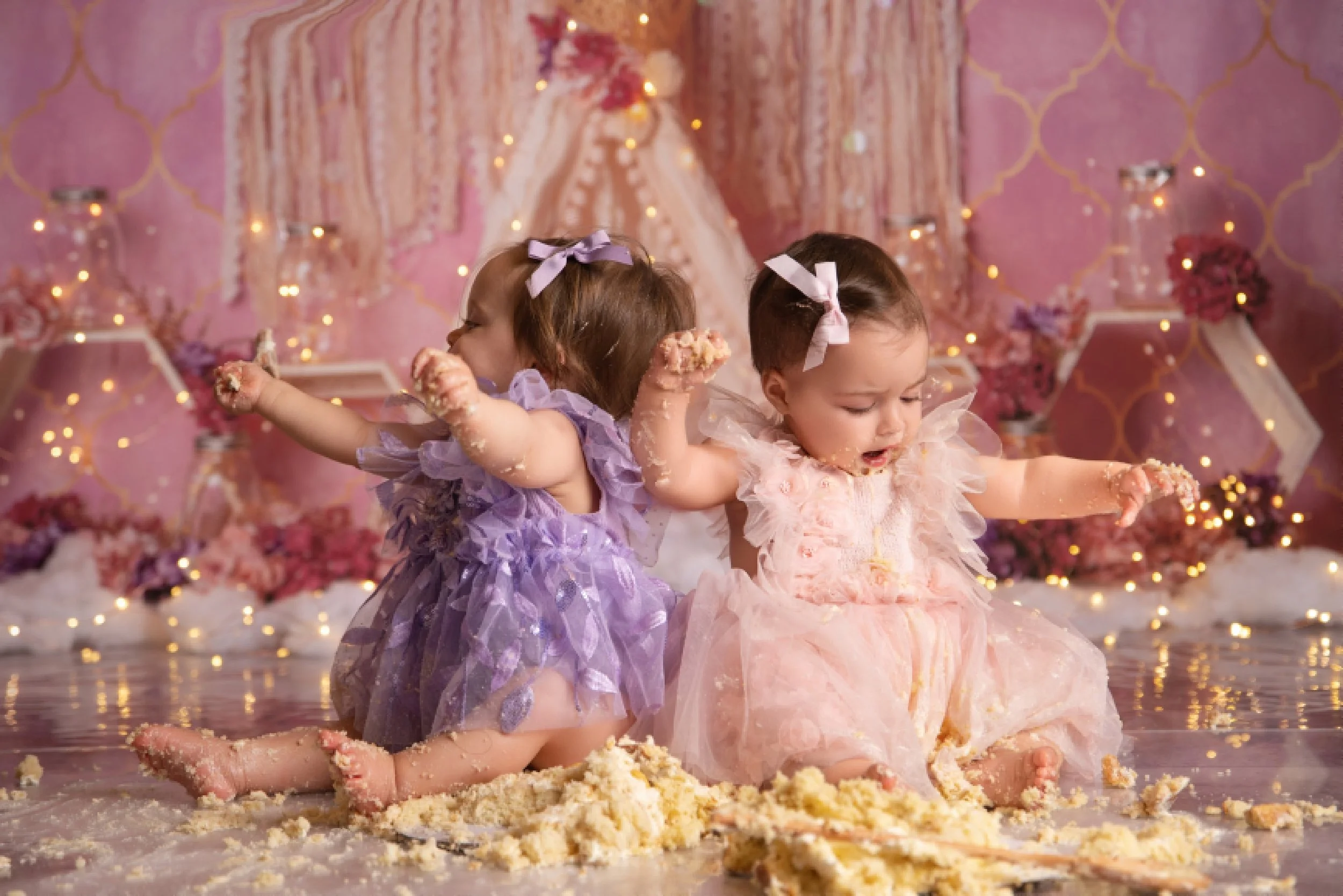Twin girls enjoying a pink and purple cake smash session in a West Windsor, NJ photography studio